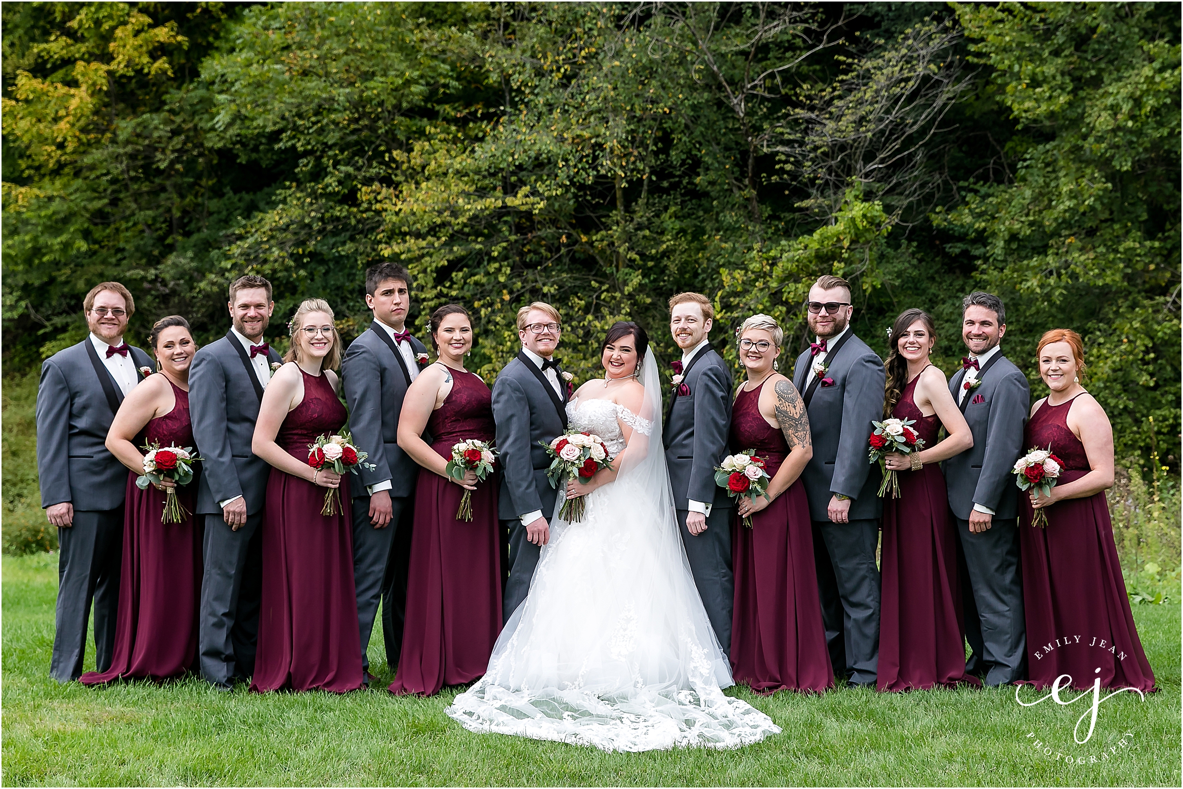 grey tuxedos and red dresses bridal wedding party bride and groom long veil lace grey suit dipping winnebago springs wedding venue in caledonia minnesota