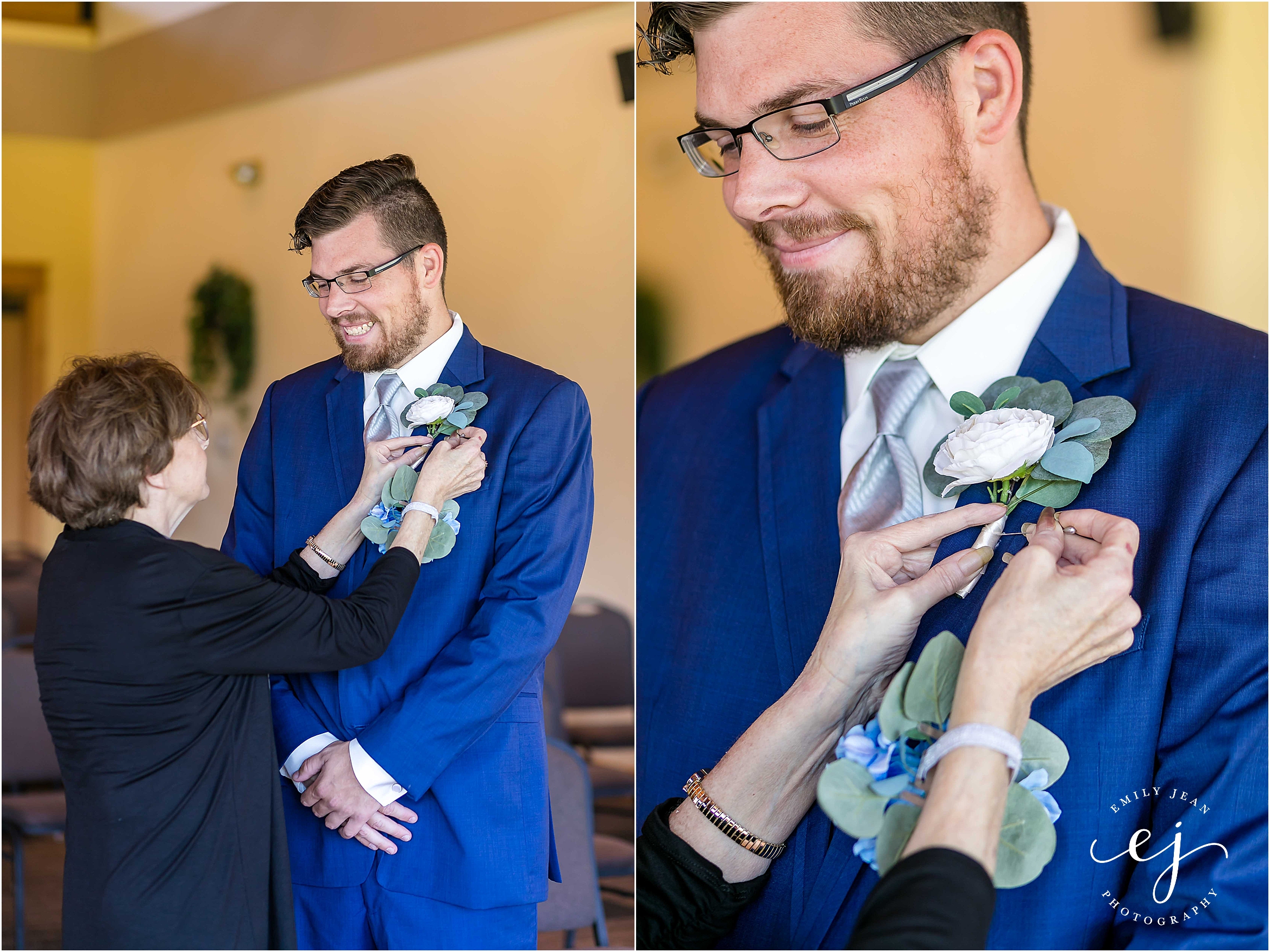 mom putting white boutonniere on groom with navy suit 