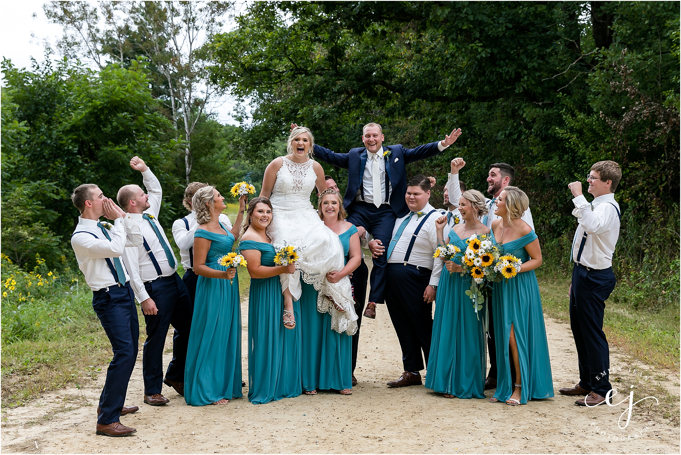 groomsmen and bridesmaids lifting up groom and bride on a country road in wisconsin
