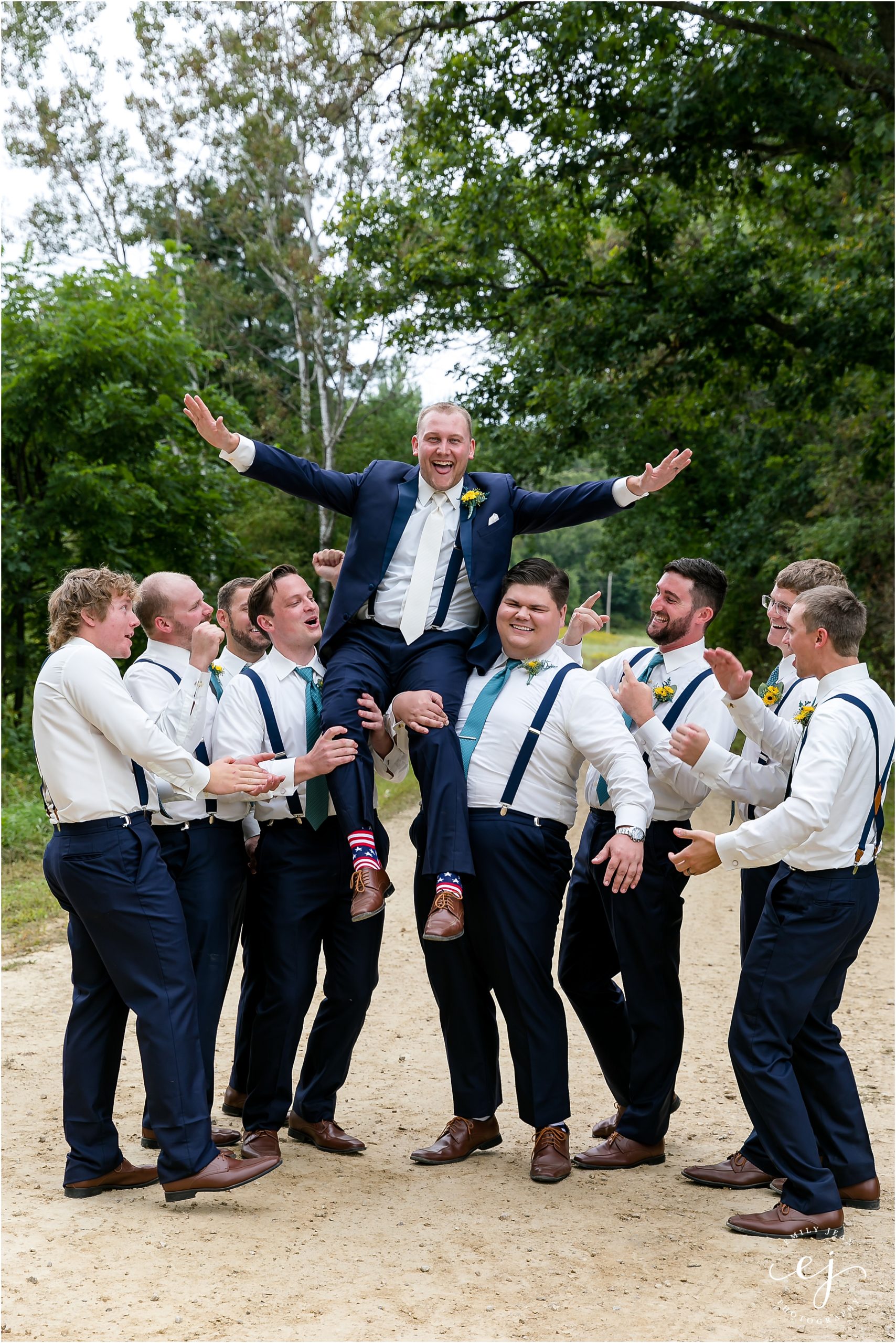 groomsmen lifting up groom on a country road in wisconsin