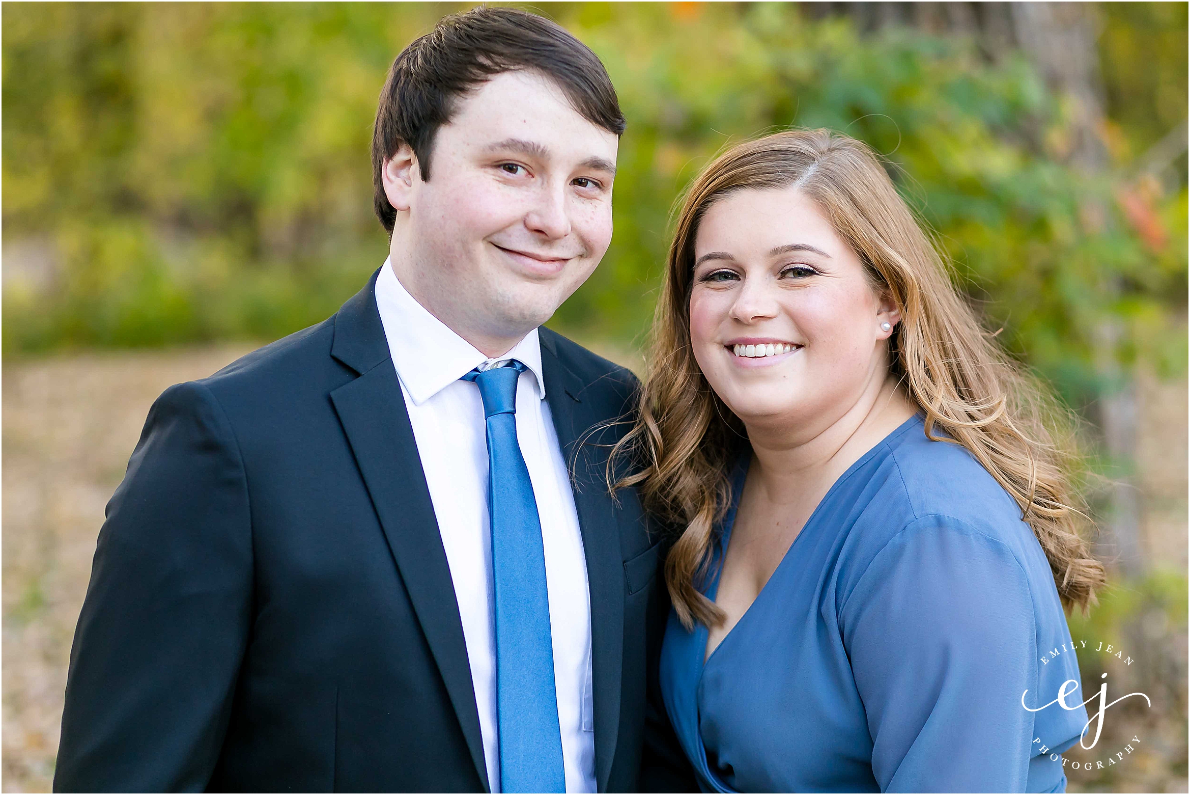 engagement session suit and tie long blue dress looking at camera smiling in park