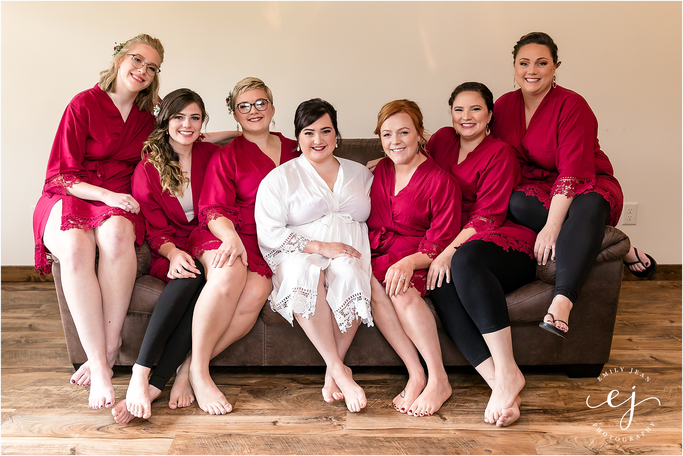 bridesmaids in red robes sitting on a couch at winnebago springs minnesota wedding