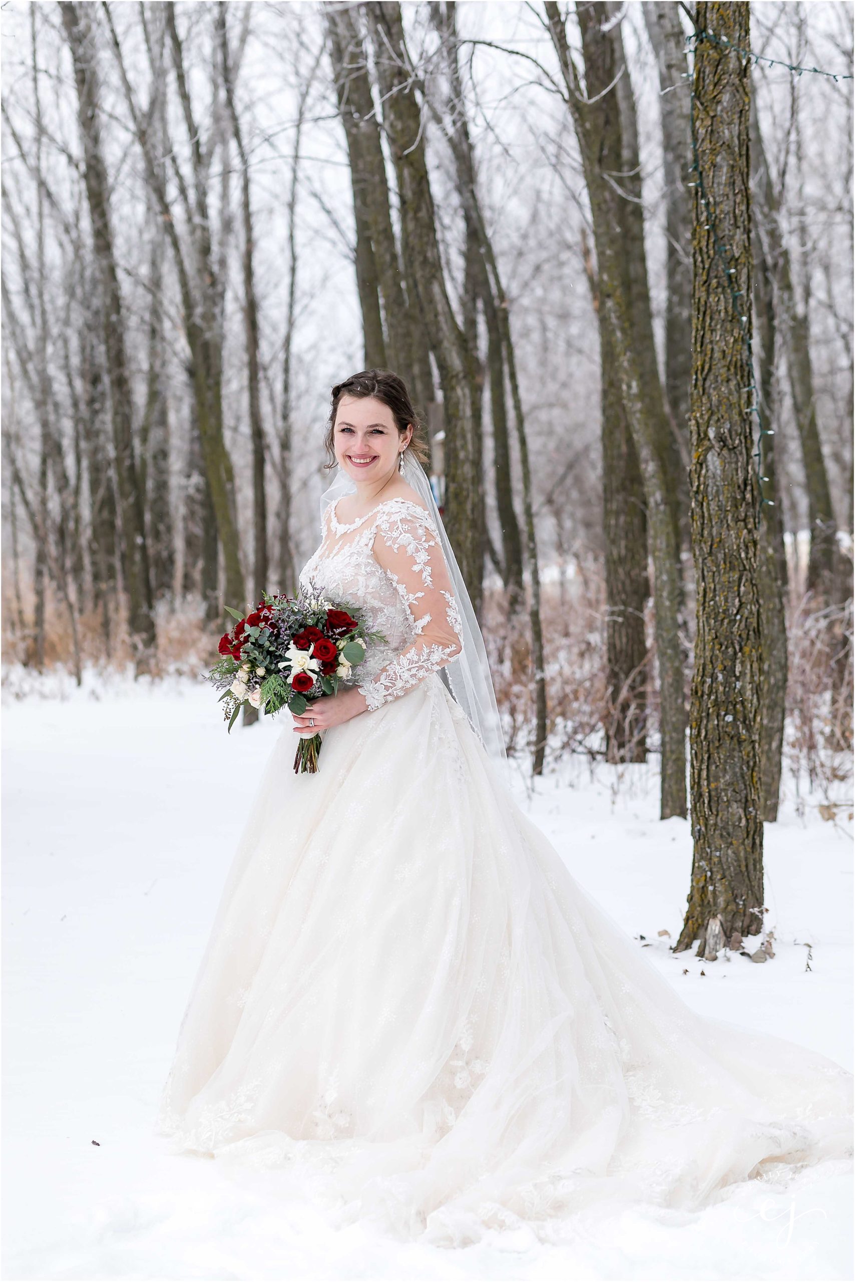 bride standing with red flowers in winter outdoors forest