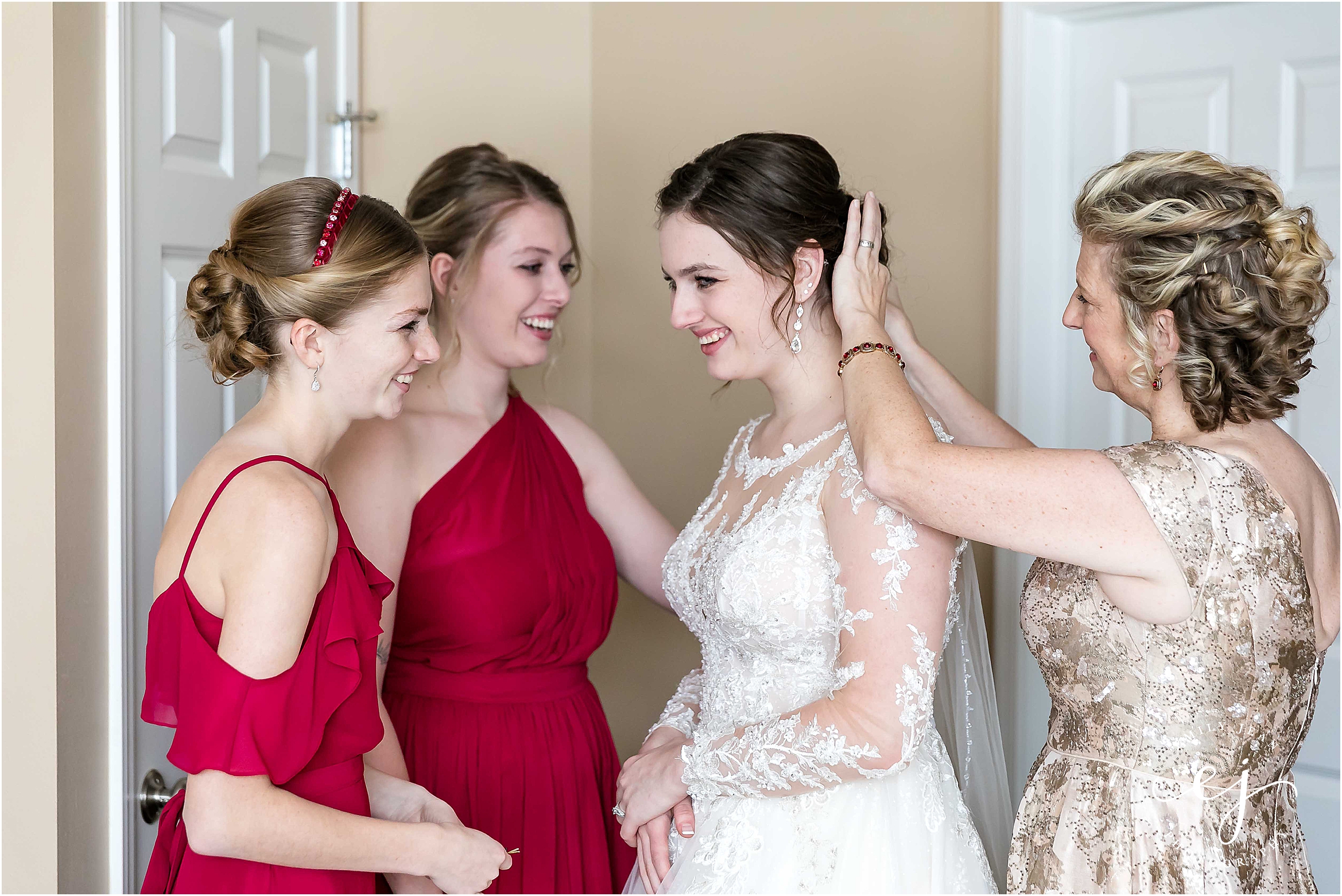 bridesmaids sisters and mom helping bride get dressed