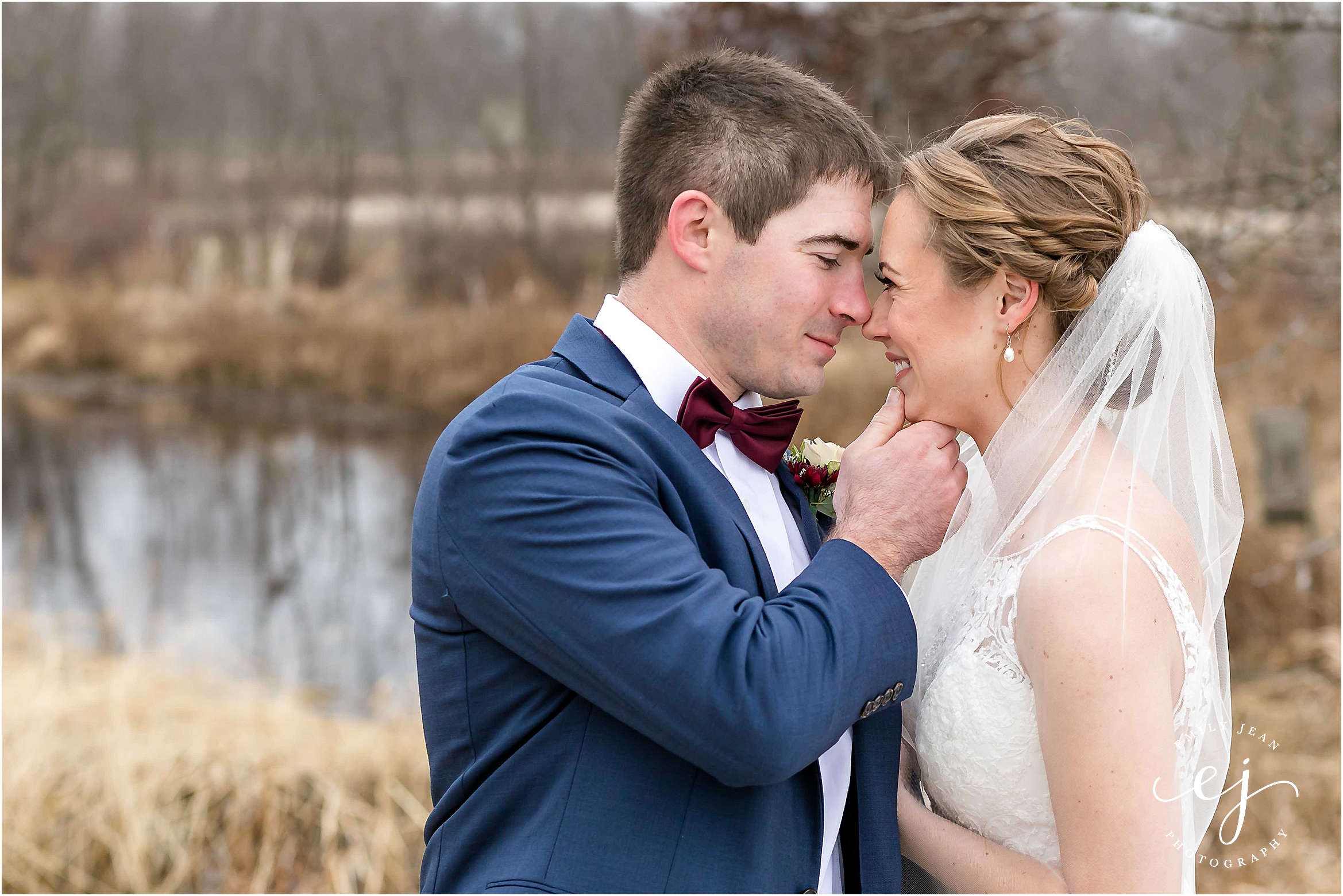 bride and groom near water winter wedding burgundy bow tie