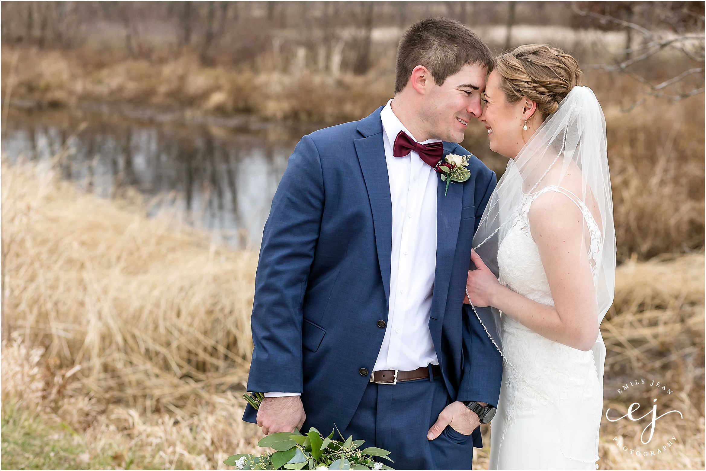 bride and groom near water winter wedding burgundy bow tie