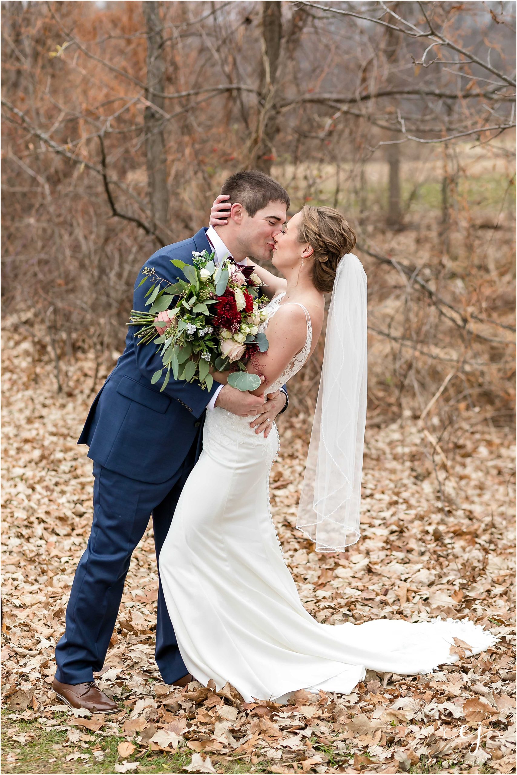 bride and groom dip outside in fall leaves navy and red