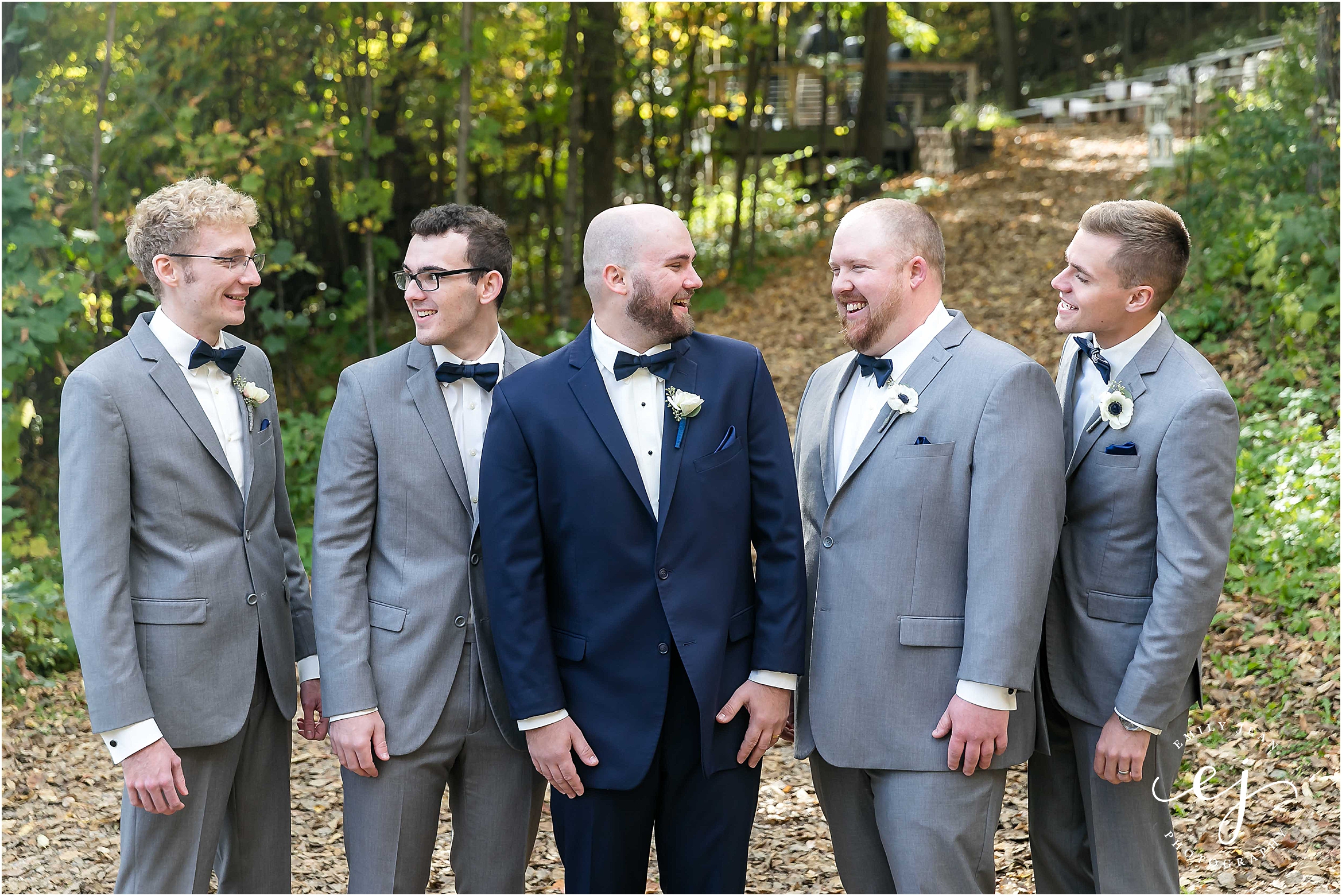 Groom and groomsmen looking at each other laughing outside at Edward farm