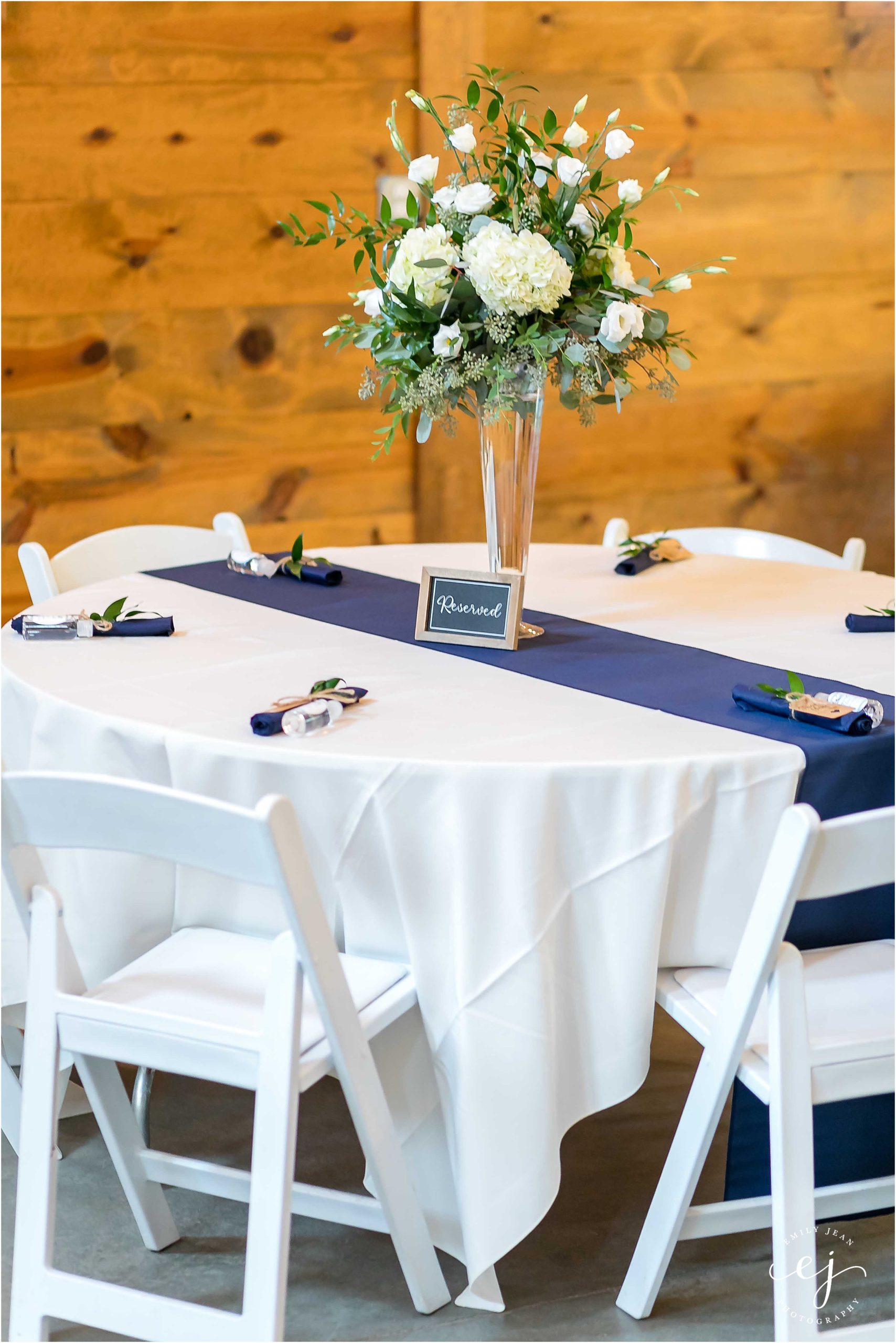 White linen tables round with navy blue satin runner and white centerpiece flowers in a glass vase edgewood farm