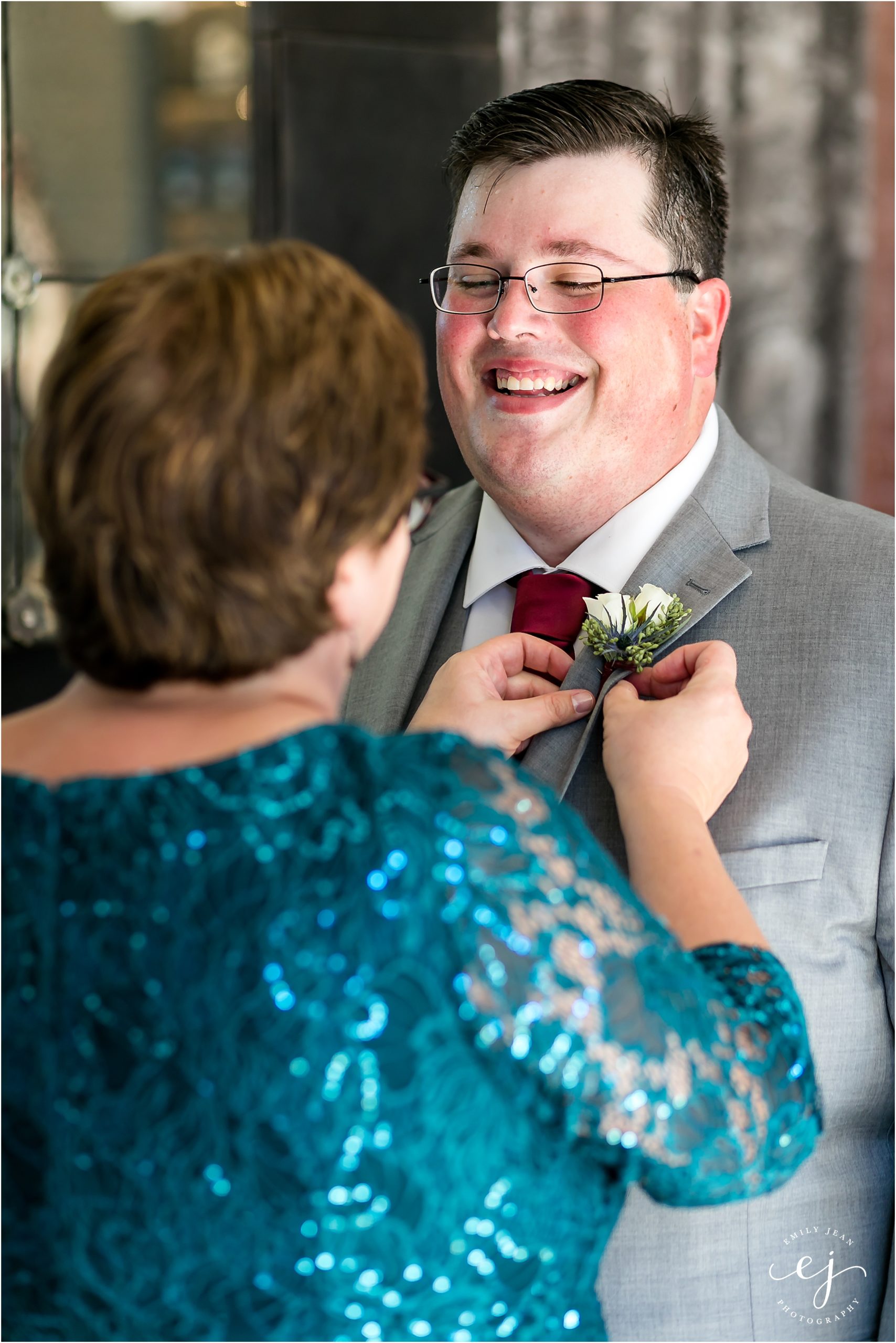 grooms mom putting on boutonniere smiling