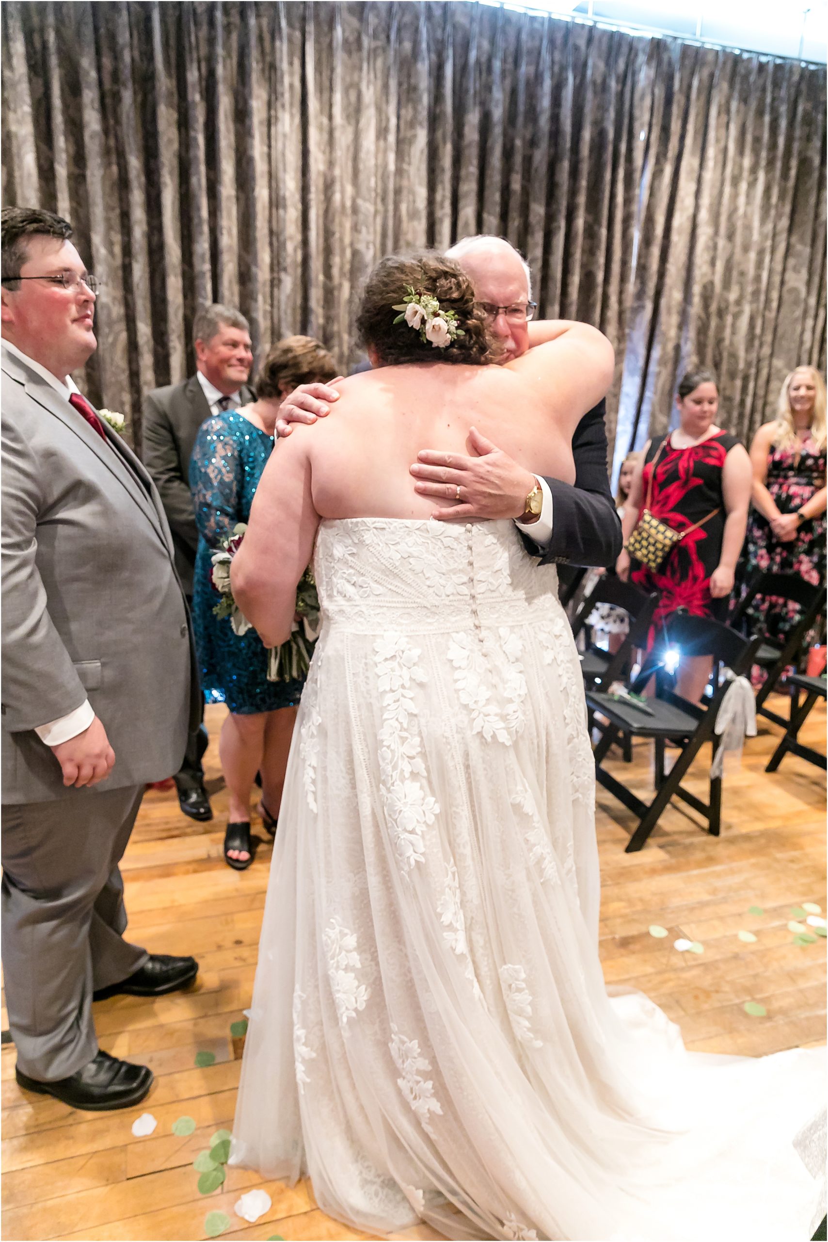 bride hugging her dad at the end of the aisle during wedding at the charmant indoors