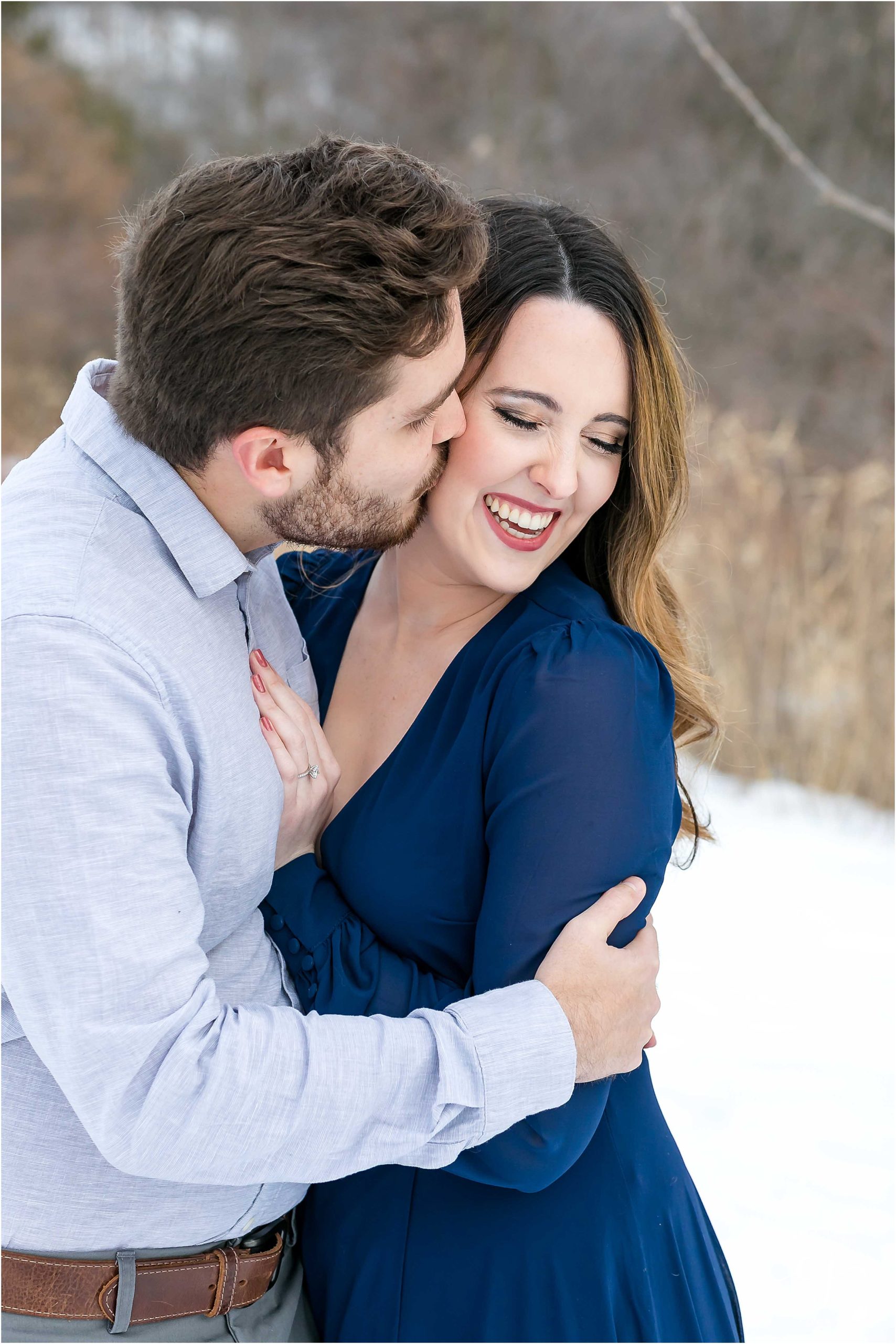 man kissing woman in blue flowy dress winter engagement la crosse