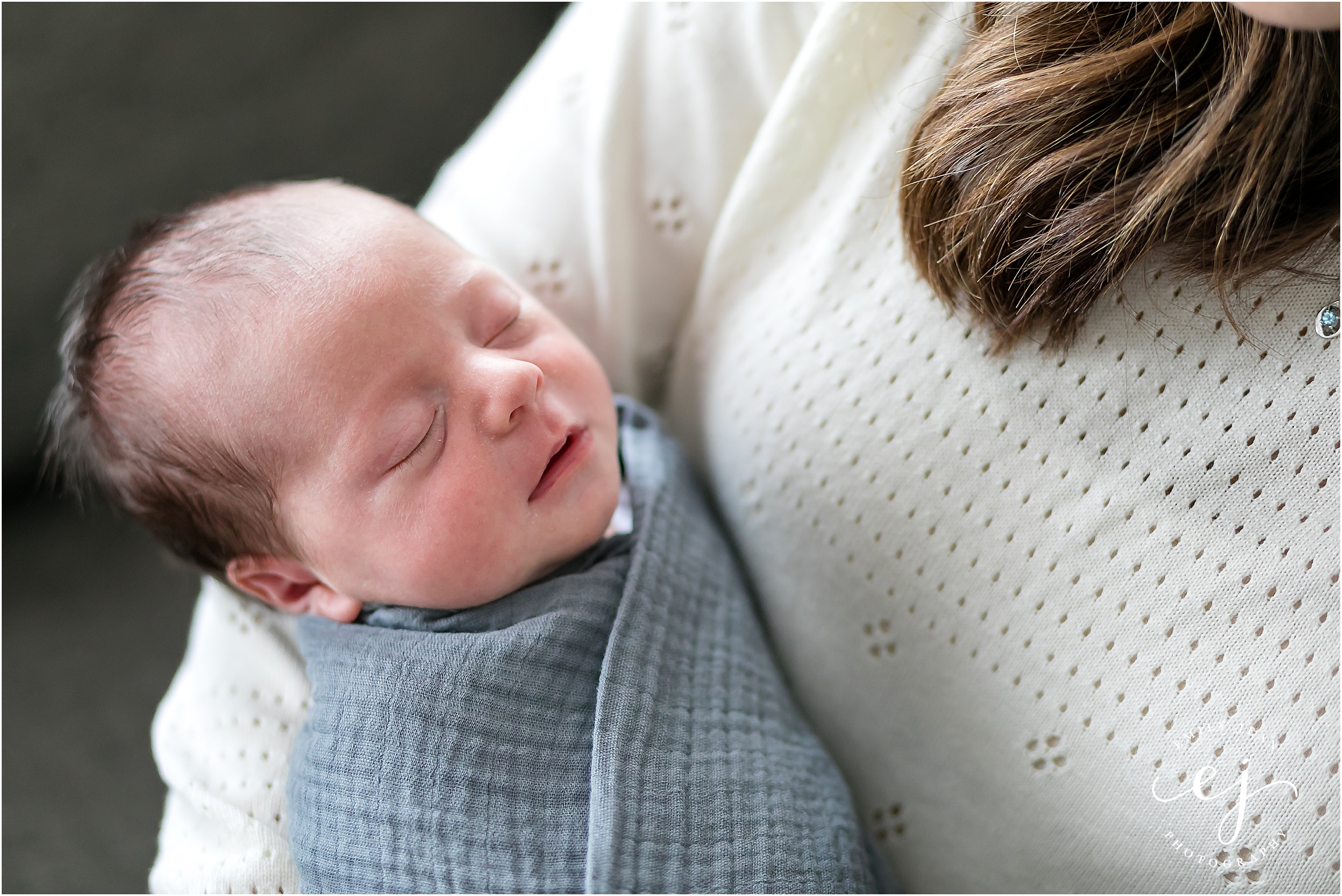 mom holding baby newborn boy in grey linen swaddle