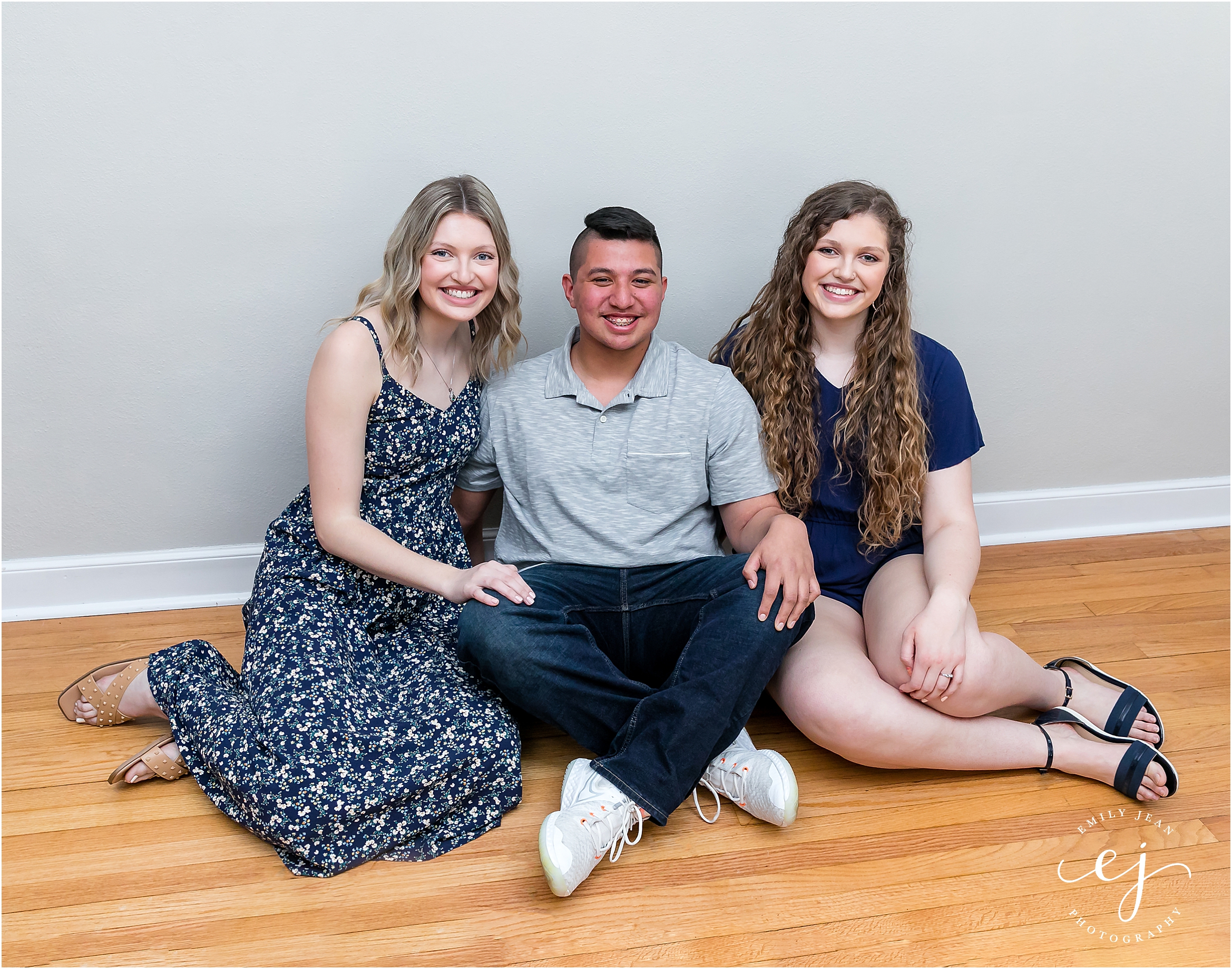 Three adult siblings sitting together family portrait across