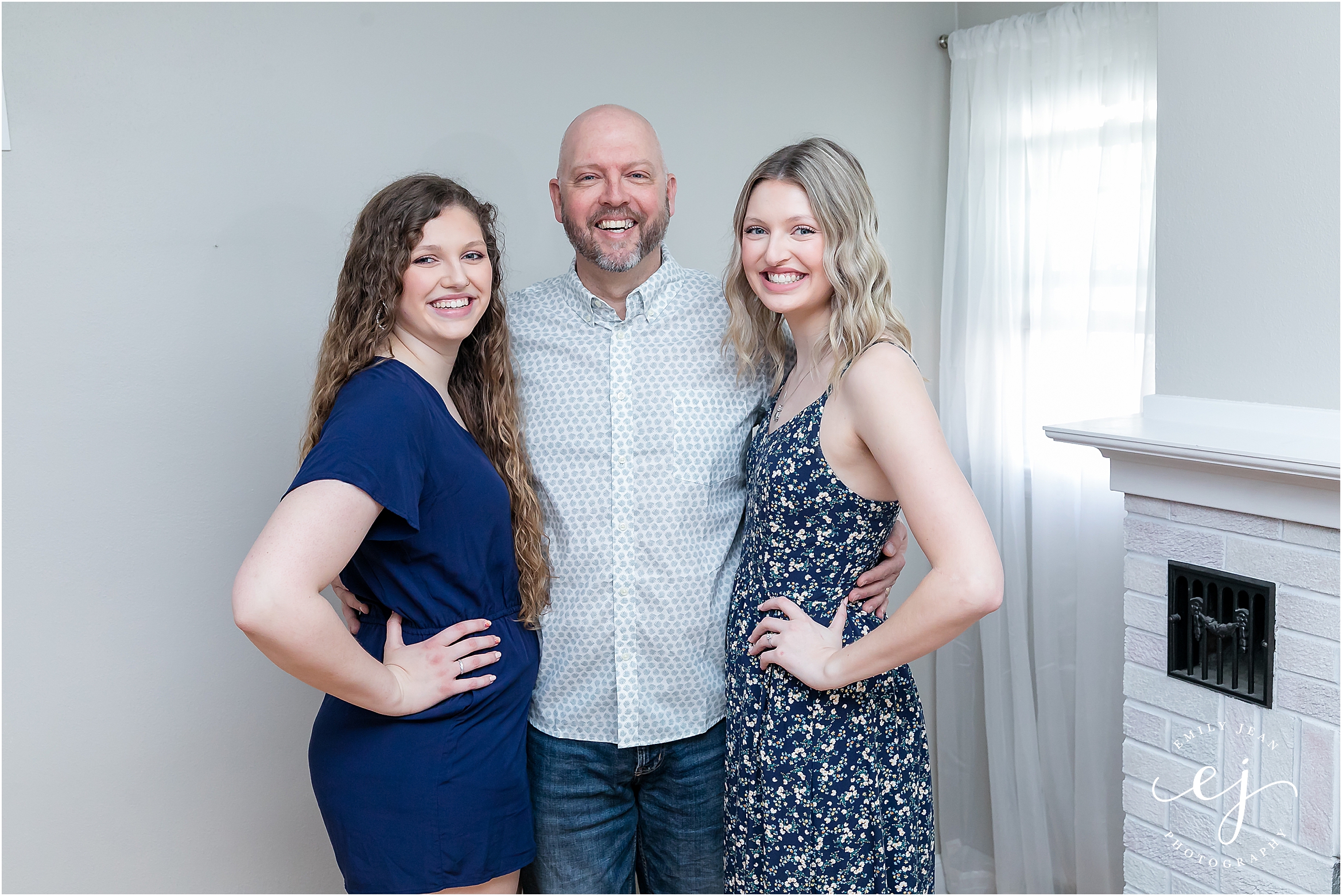 A dad standing with his two adult daughters smiling at the camera