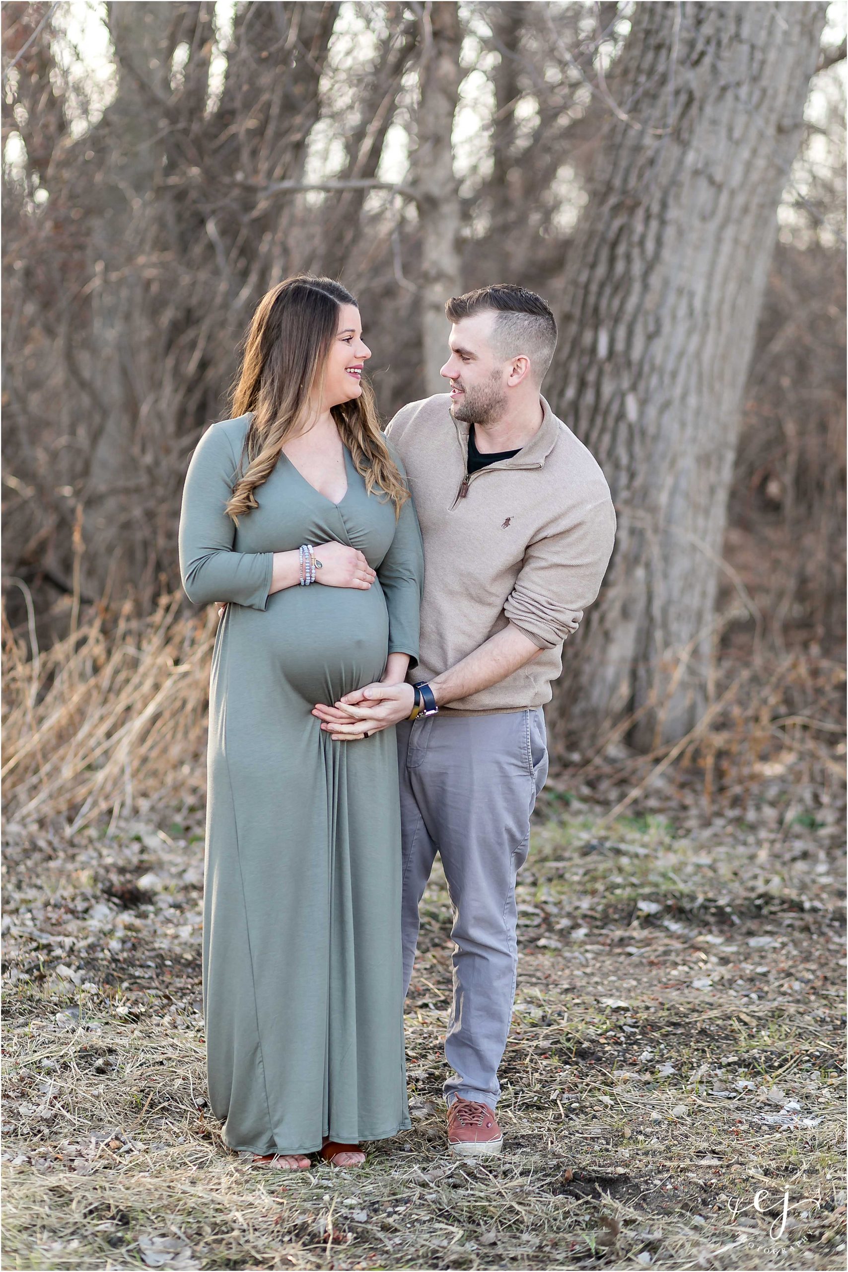 pregnant woman in light green knit dress pregnant with husband holding belly