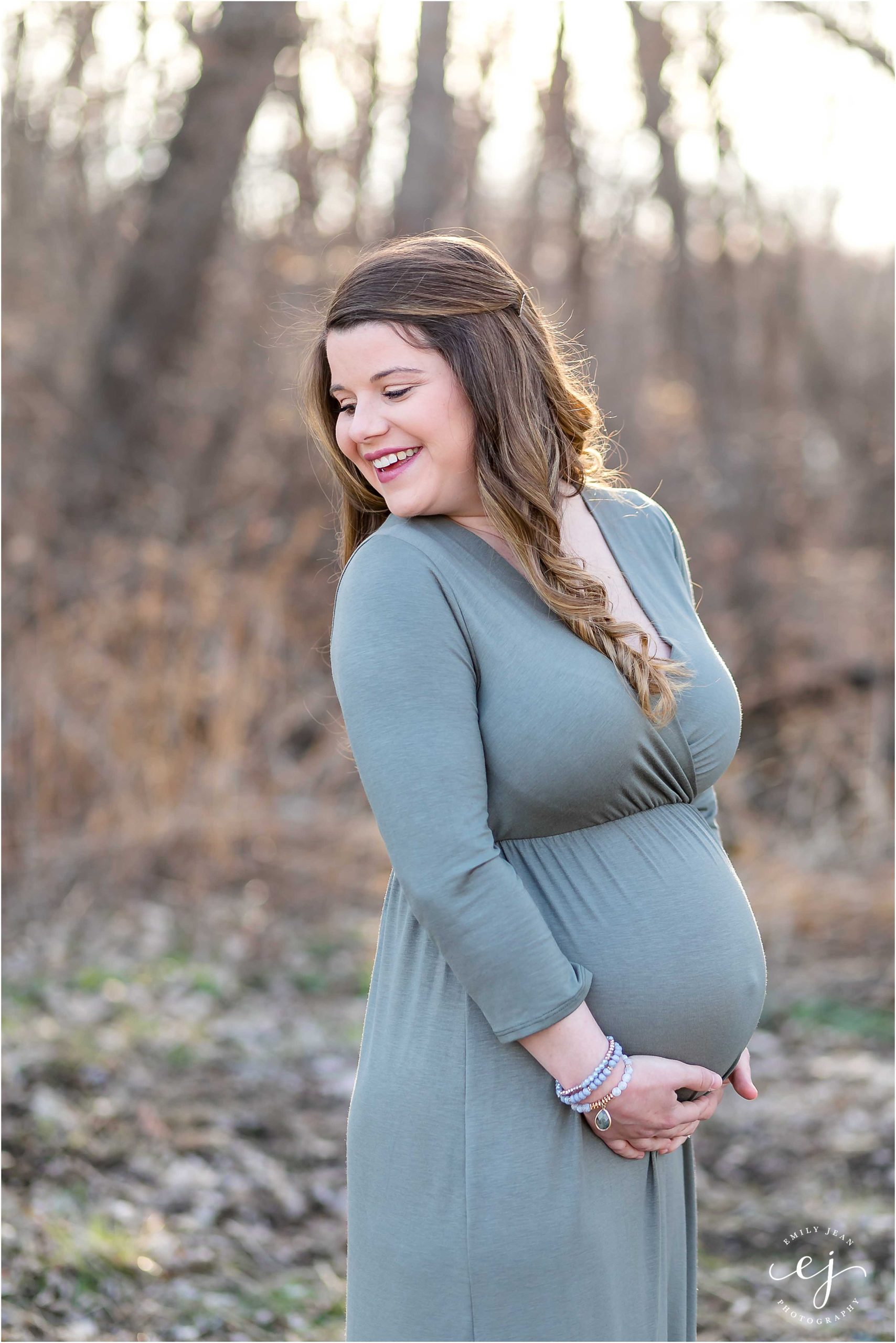 pregnant woman looking behind herself smiling and holding belly