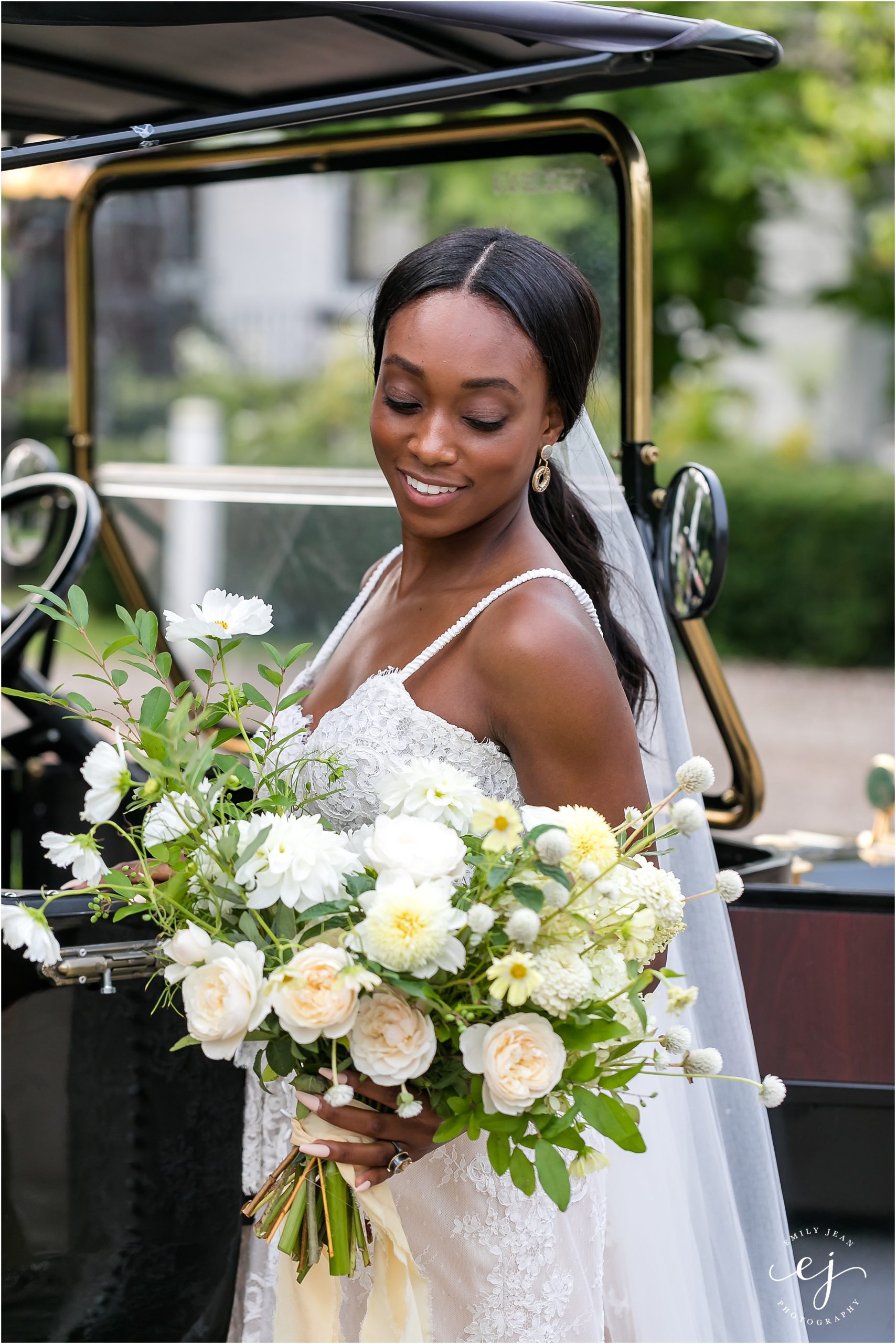 black bride with straight long hair standing with old car laughing