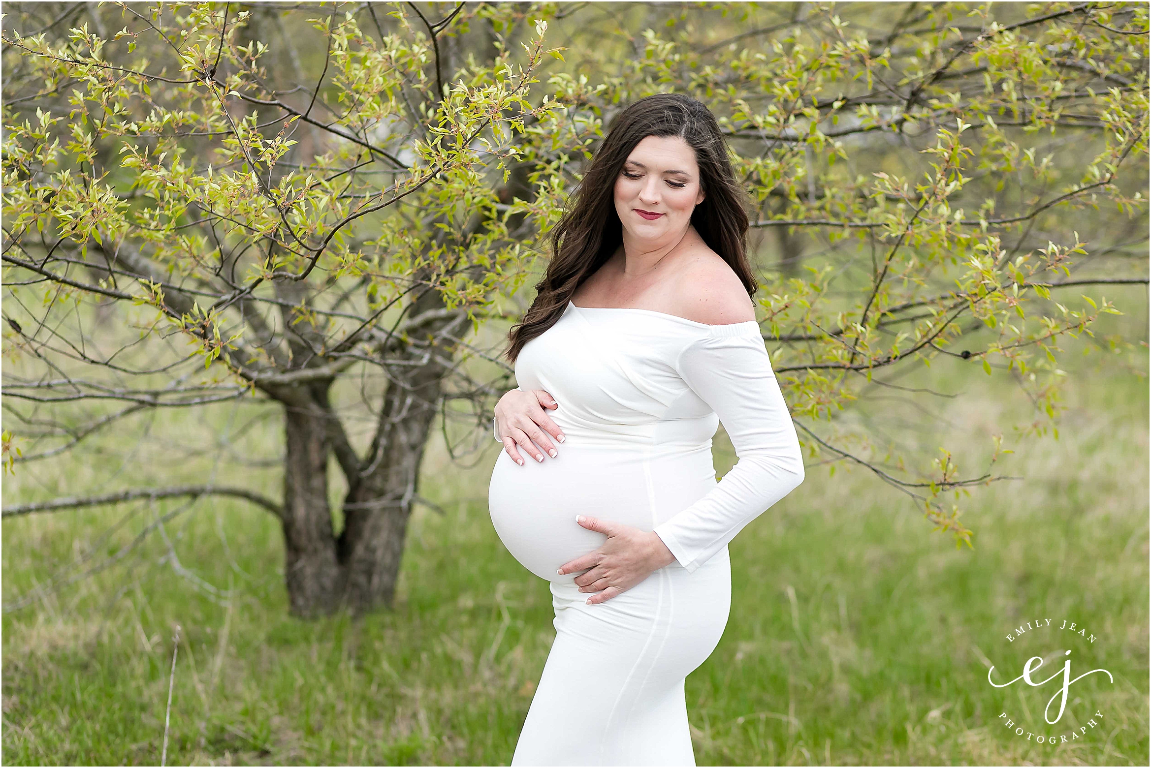 Maternity photos women wearing white dress with long brown hair in the spring time