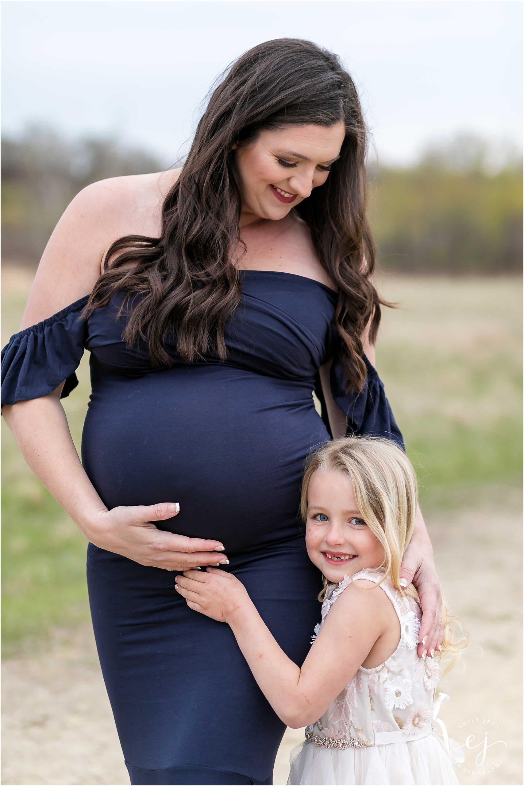 Maternity session mom with her little blonde daughter hugging her leg