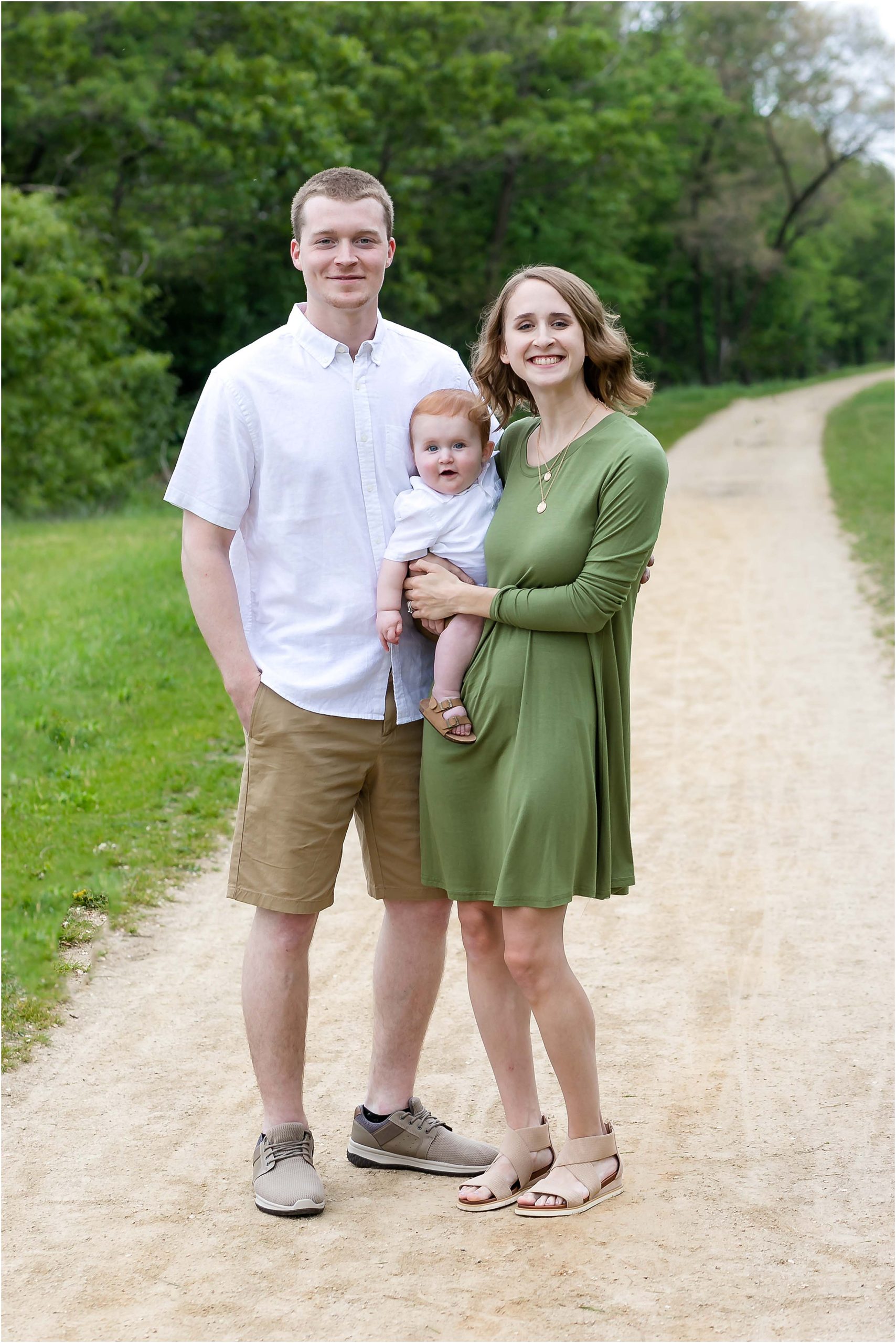 family of three smiling at the camera on trail