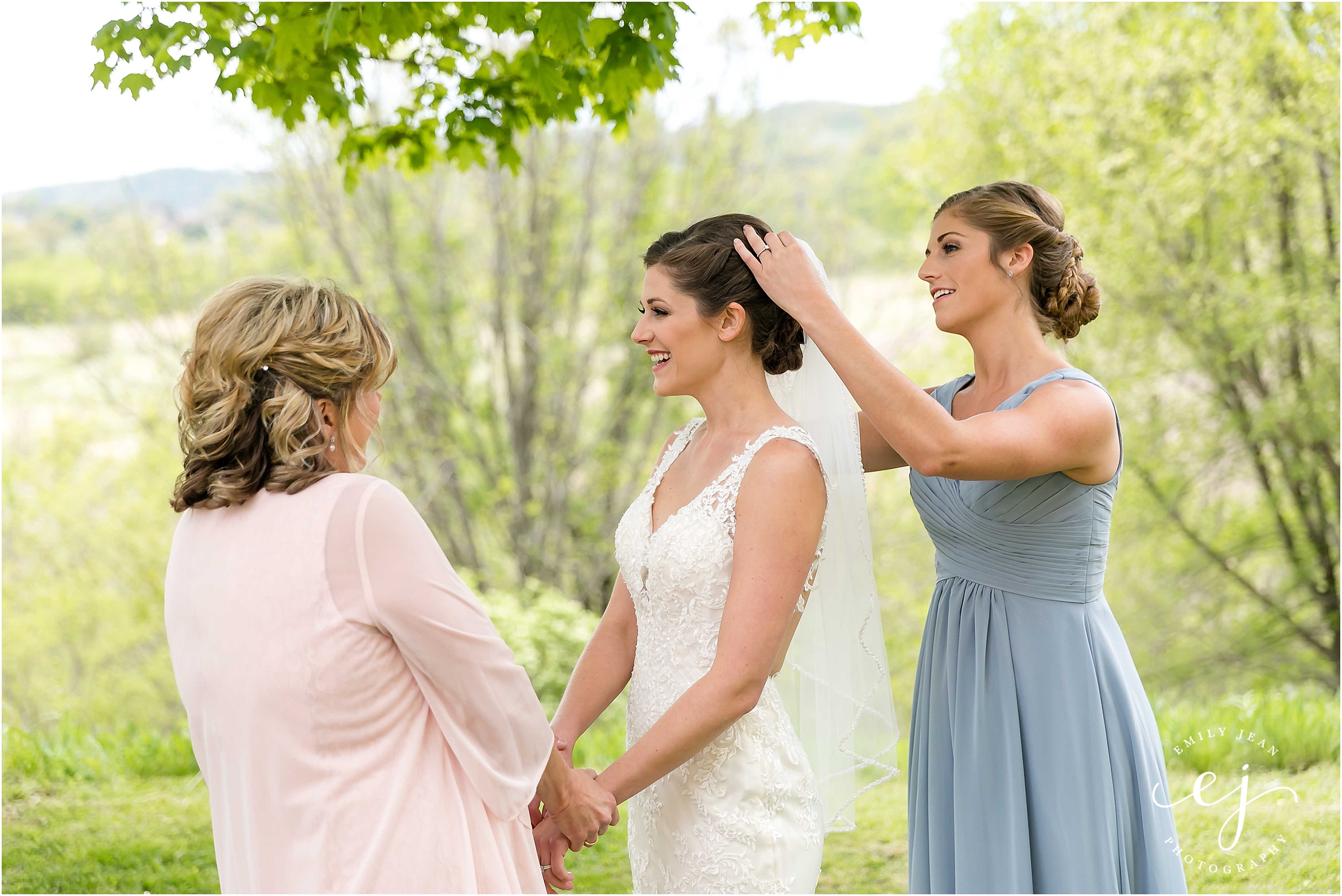 mom and maid of honor helping bride get dressed