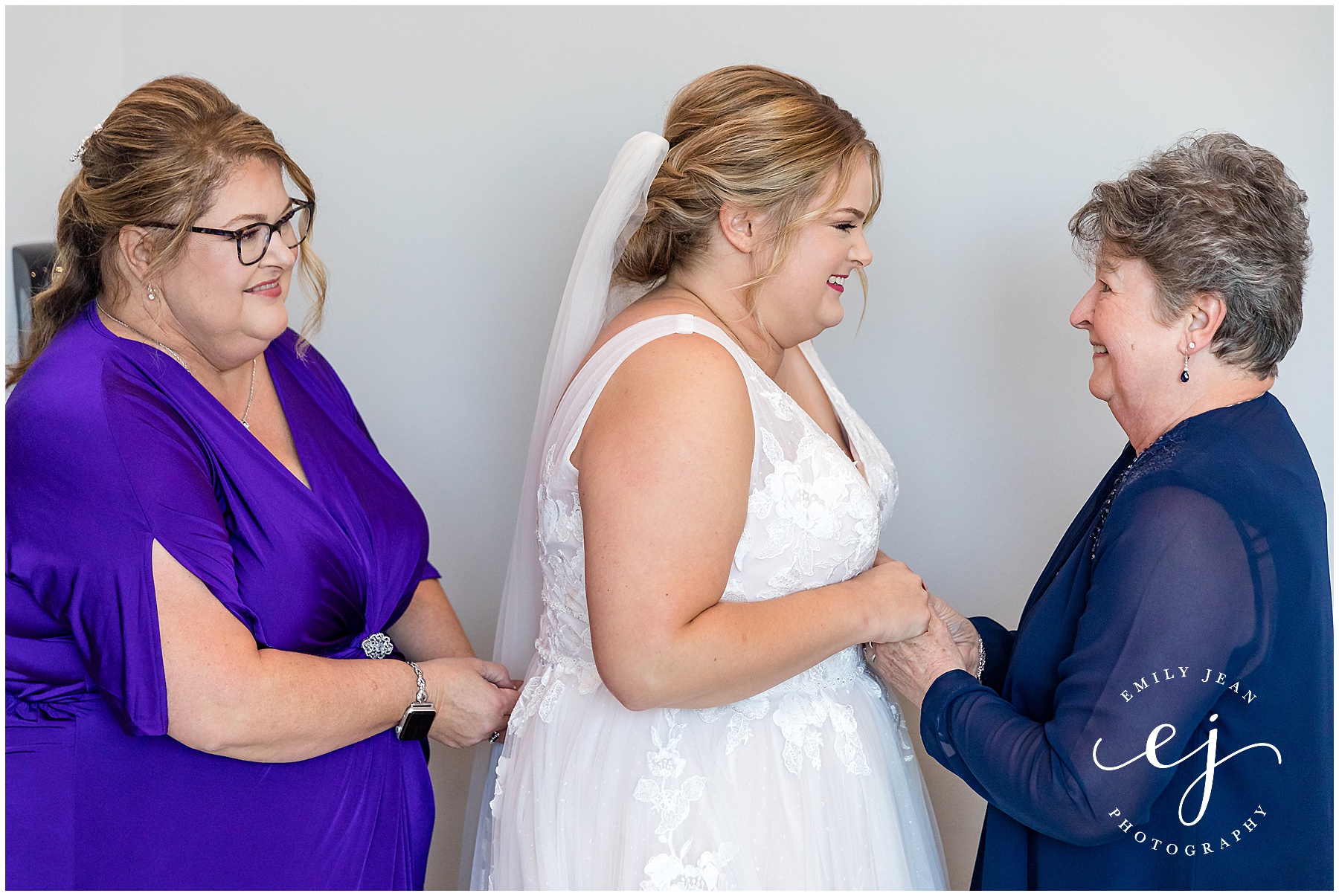 mom and grandma helping bride get in her dress