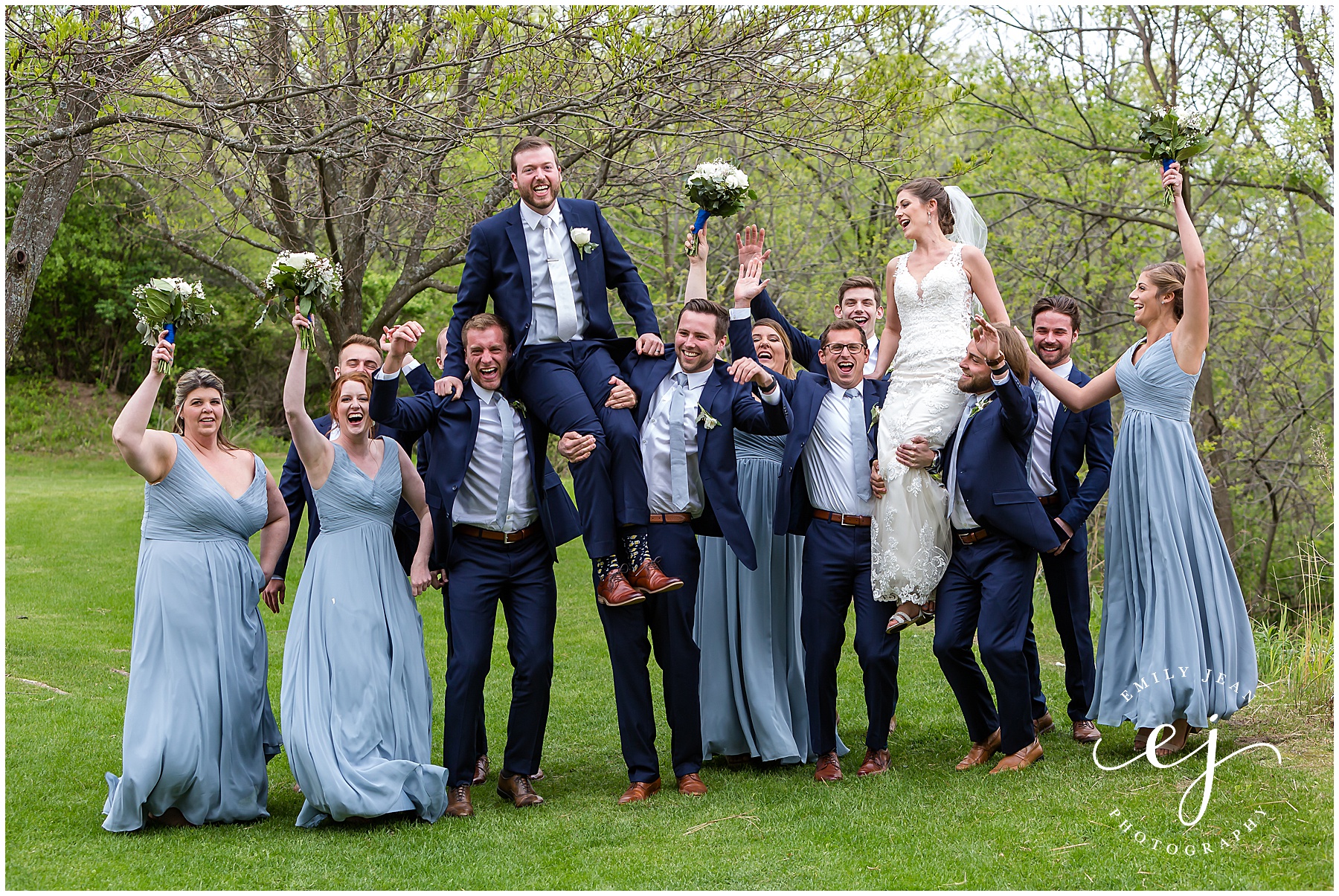 wedding party holding the bride and groom in the air on shoulders
