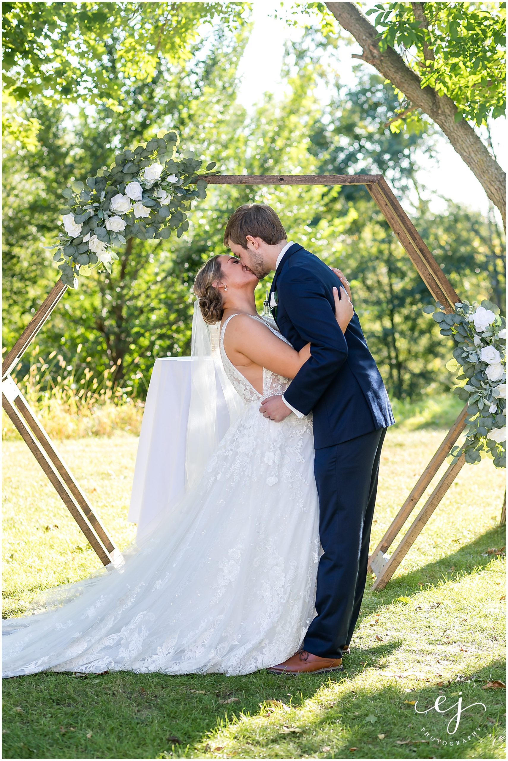 first kiss at altar hexagon arch outdoor wedding