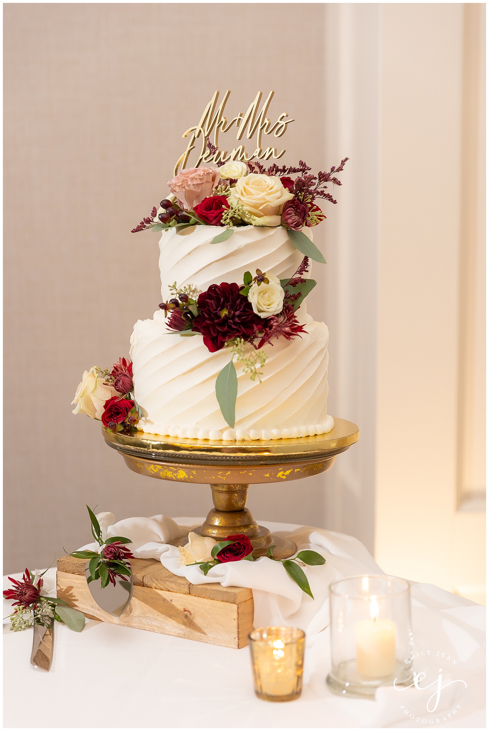 two tier white wedding cake with real flowers on a gold stand