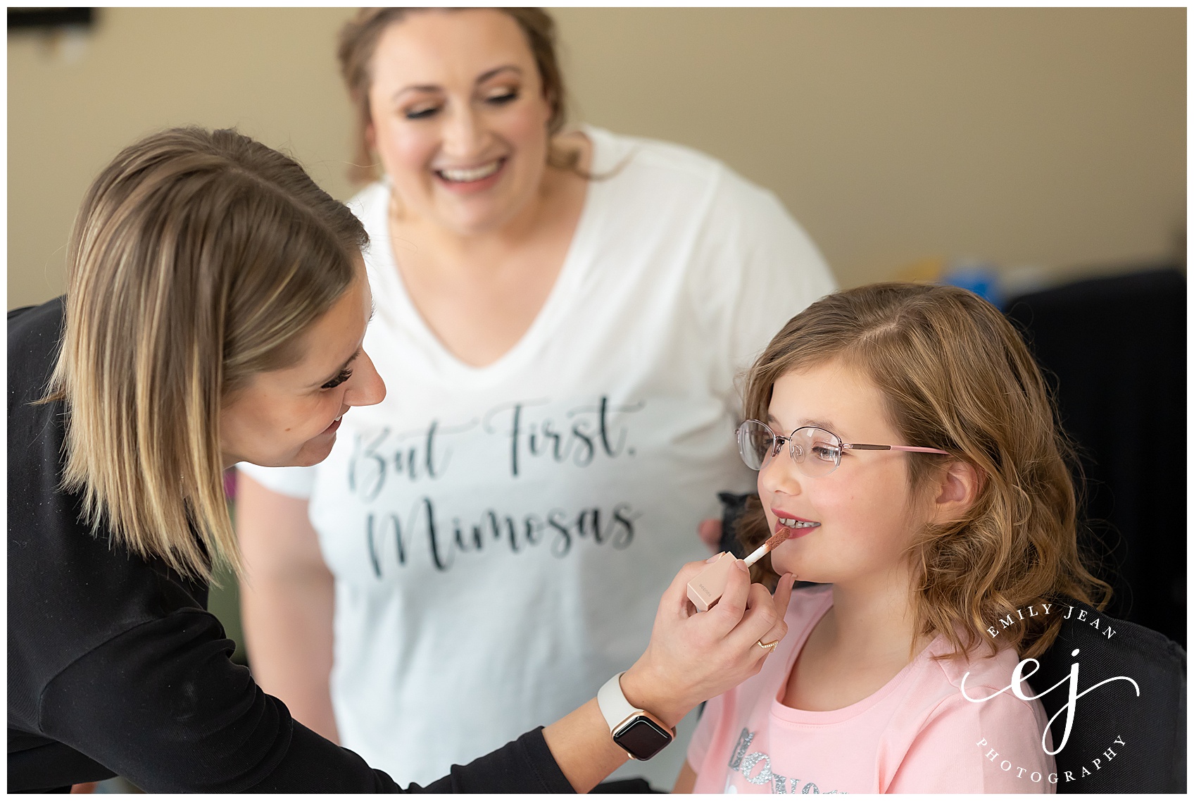 makeup by sarah koblitz putting makeup on flower girl with bride looking and smiling