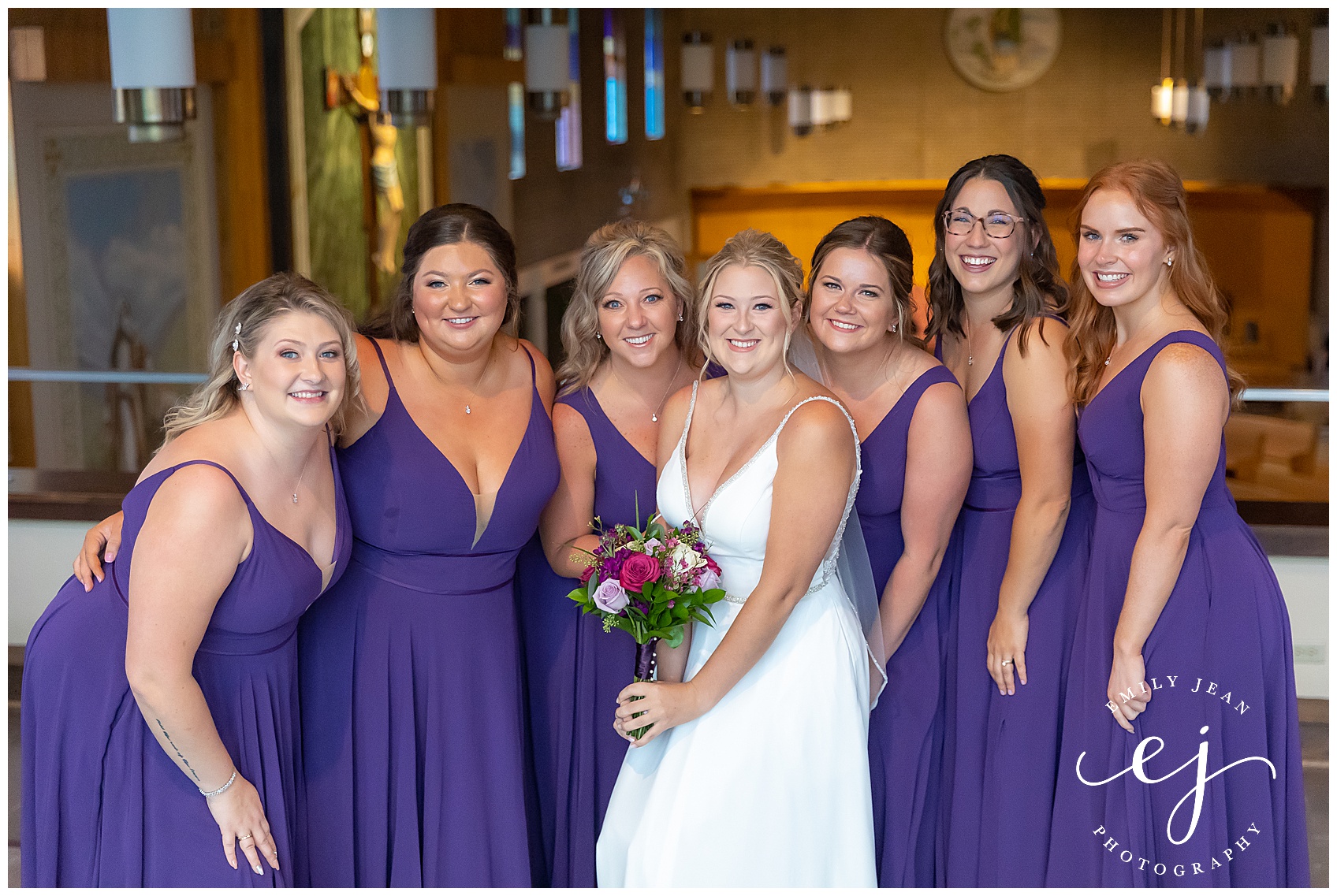 bride and bridesmaids at church smiling wearing purple