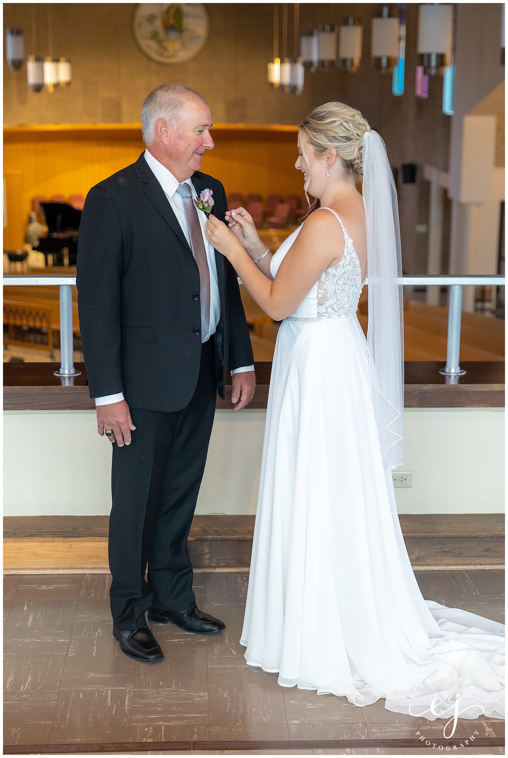 bride putting boutonniere on her dad before wedding