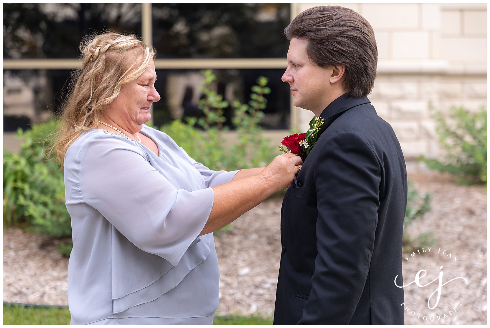 mother putting boutonniere on groom