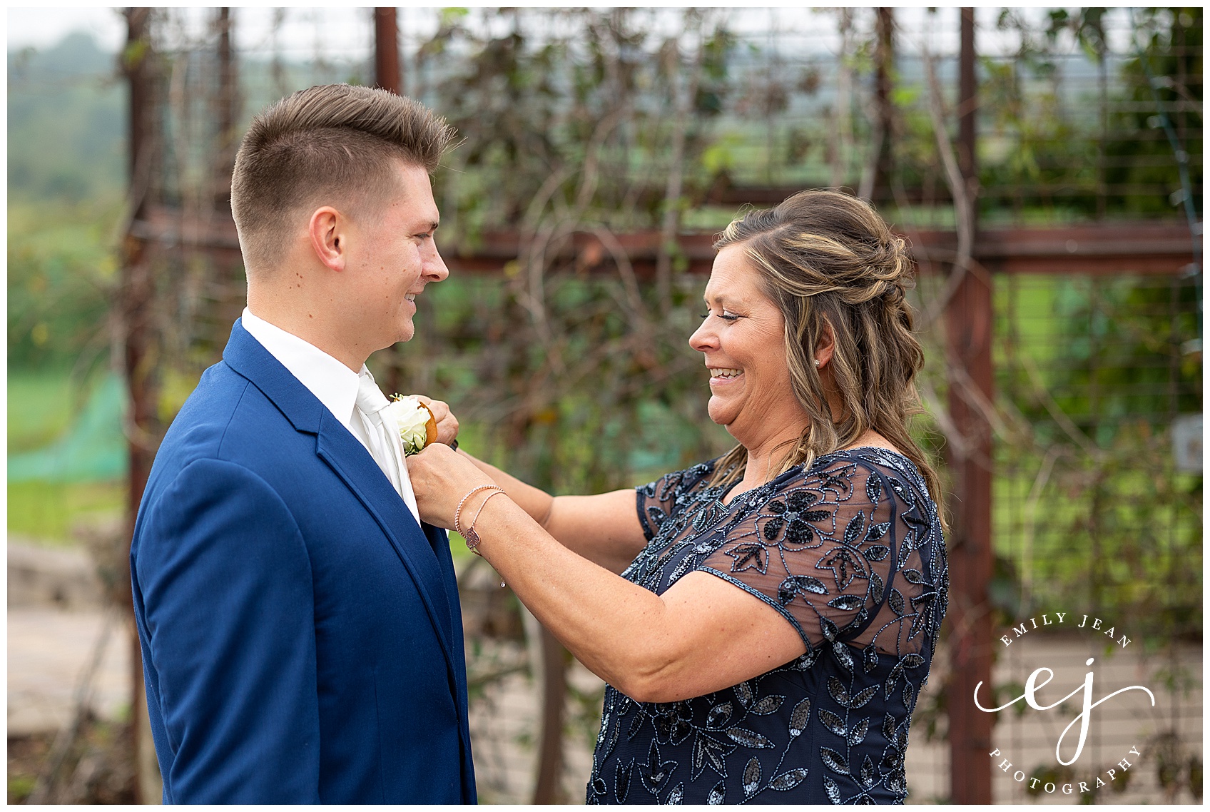 mother of groom putting boutonniere 