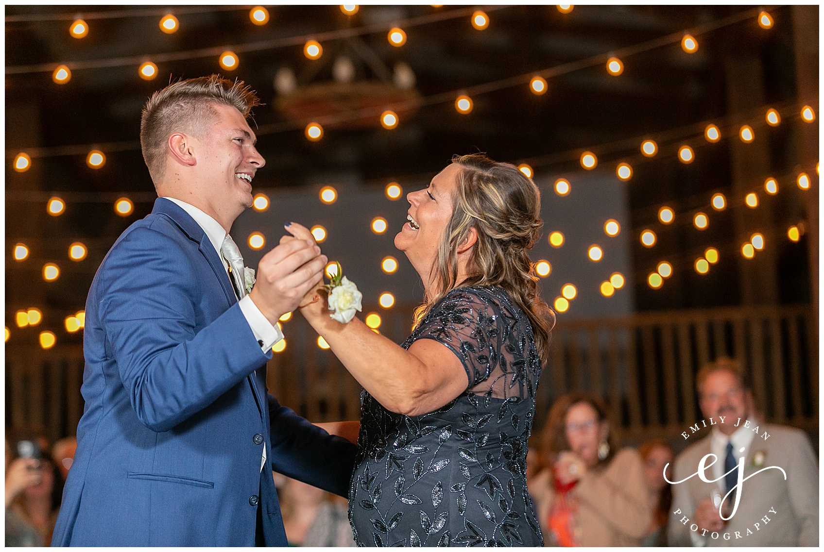 groom and mom dancing under twinkle lights