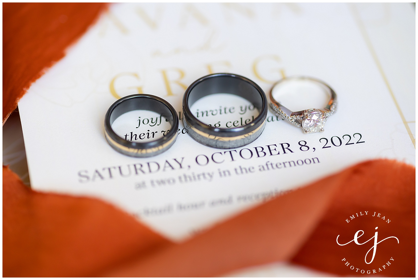 wedding rings and invitation with orange ribbon