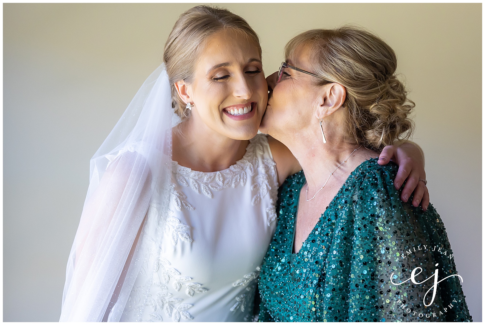 mother of bride gives her a kiss on the cheek