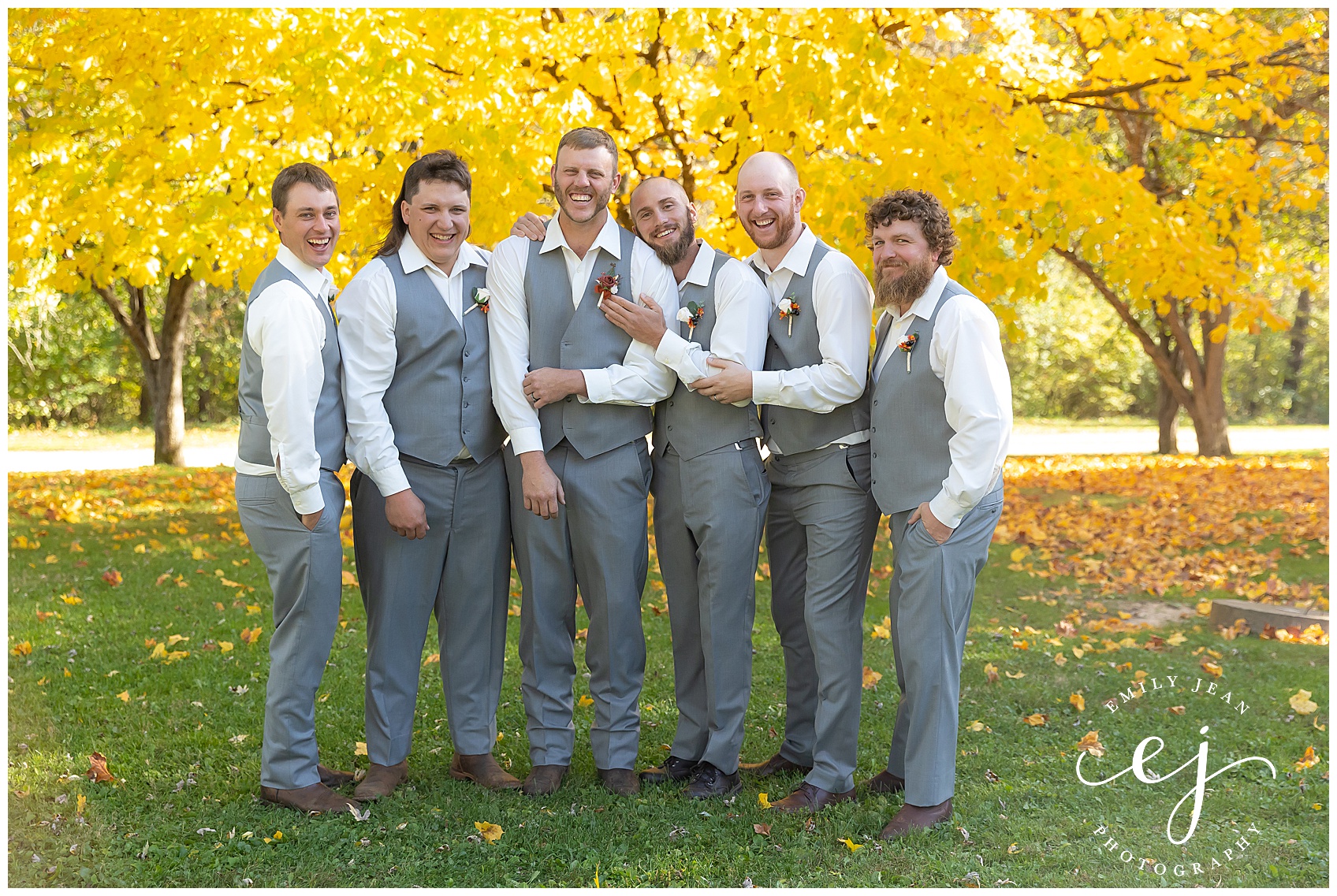 groomsmen laughing wearing grey vest and white shirts