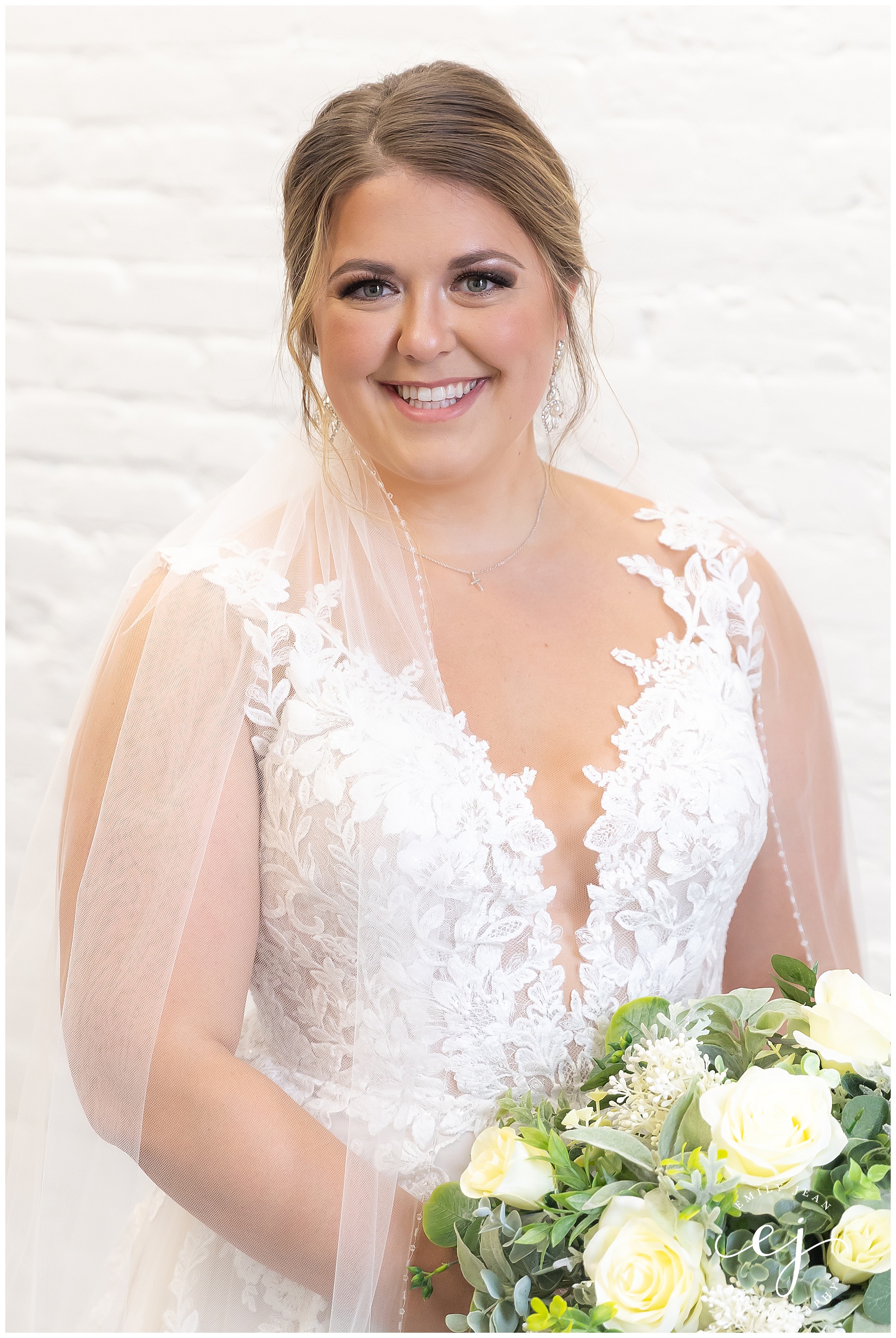 bride smiling and looking at the camera with long veil and floral wedding dress