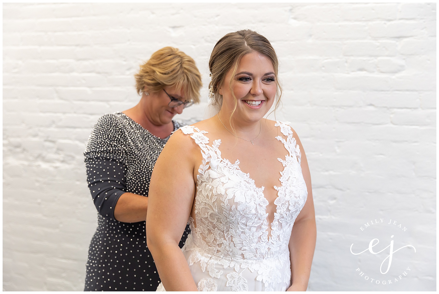 mother of the bride helping put on wedding dress at makeup by sarah koblitz