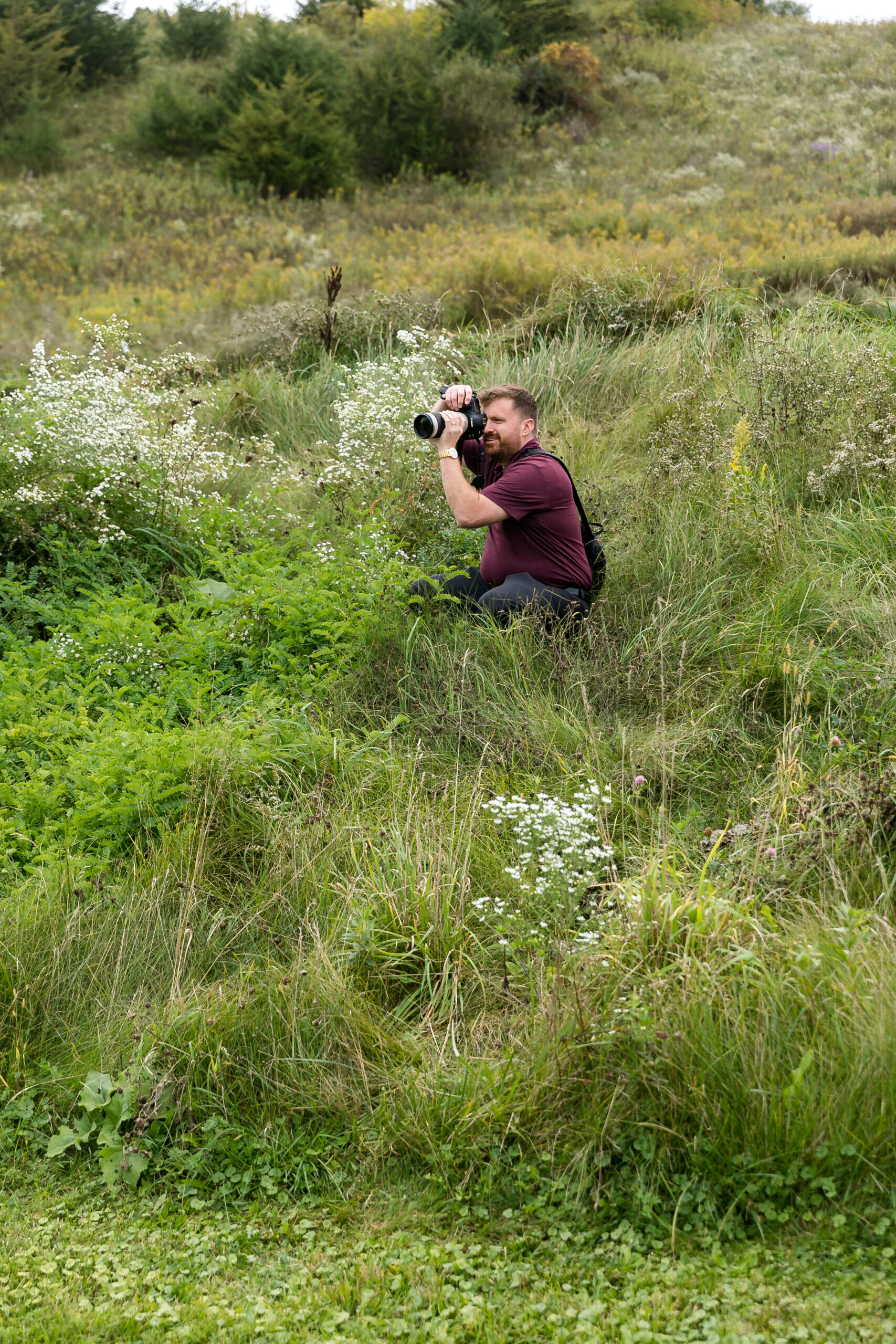 ben branson crouched in a field getting a second angle with his camera