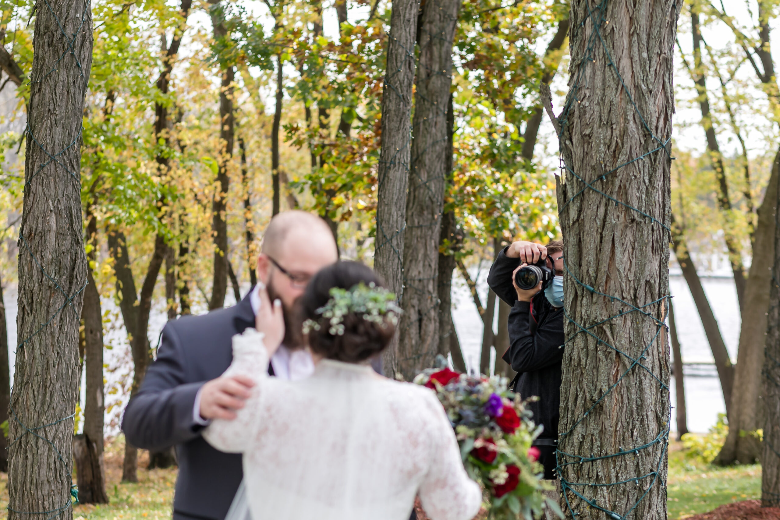 ben branson at celebrations on the river getting a second angle of a bride and groom from behind a tree